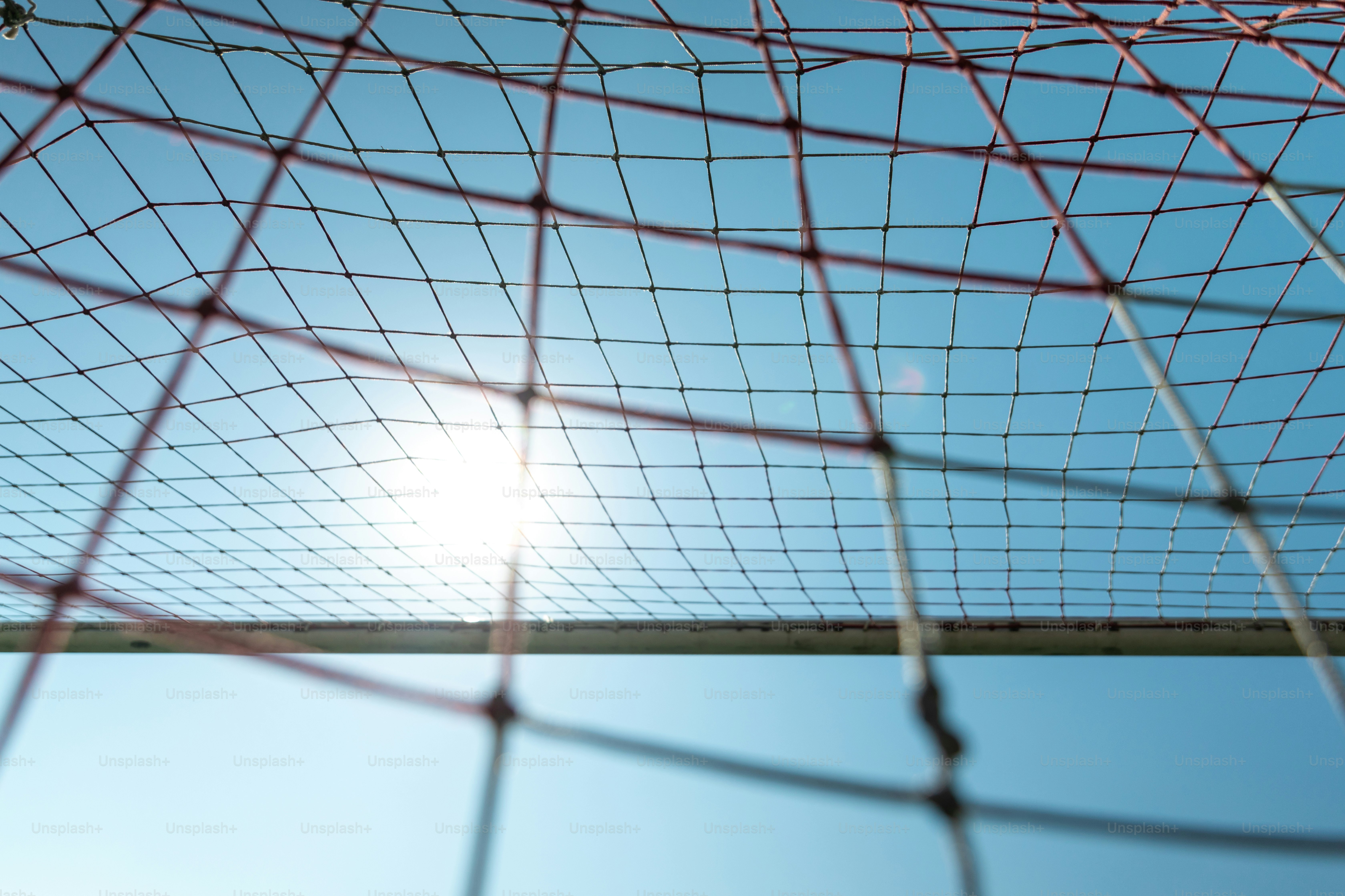 Die Sonne scheint durch ein Sportnetz gegen den blauen Himmel