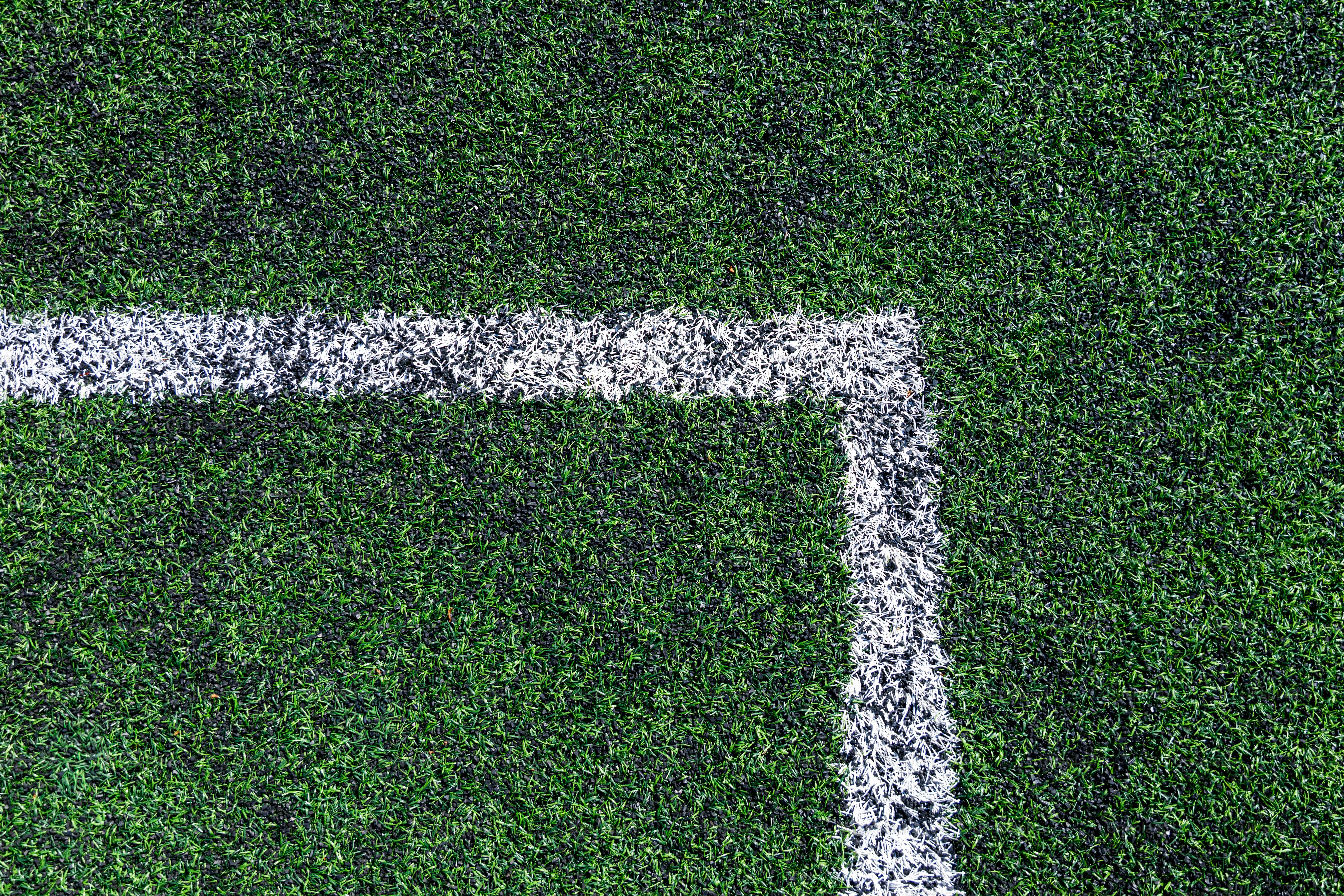 Ecke eines grünen Sportfeldes mit weißen Linien