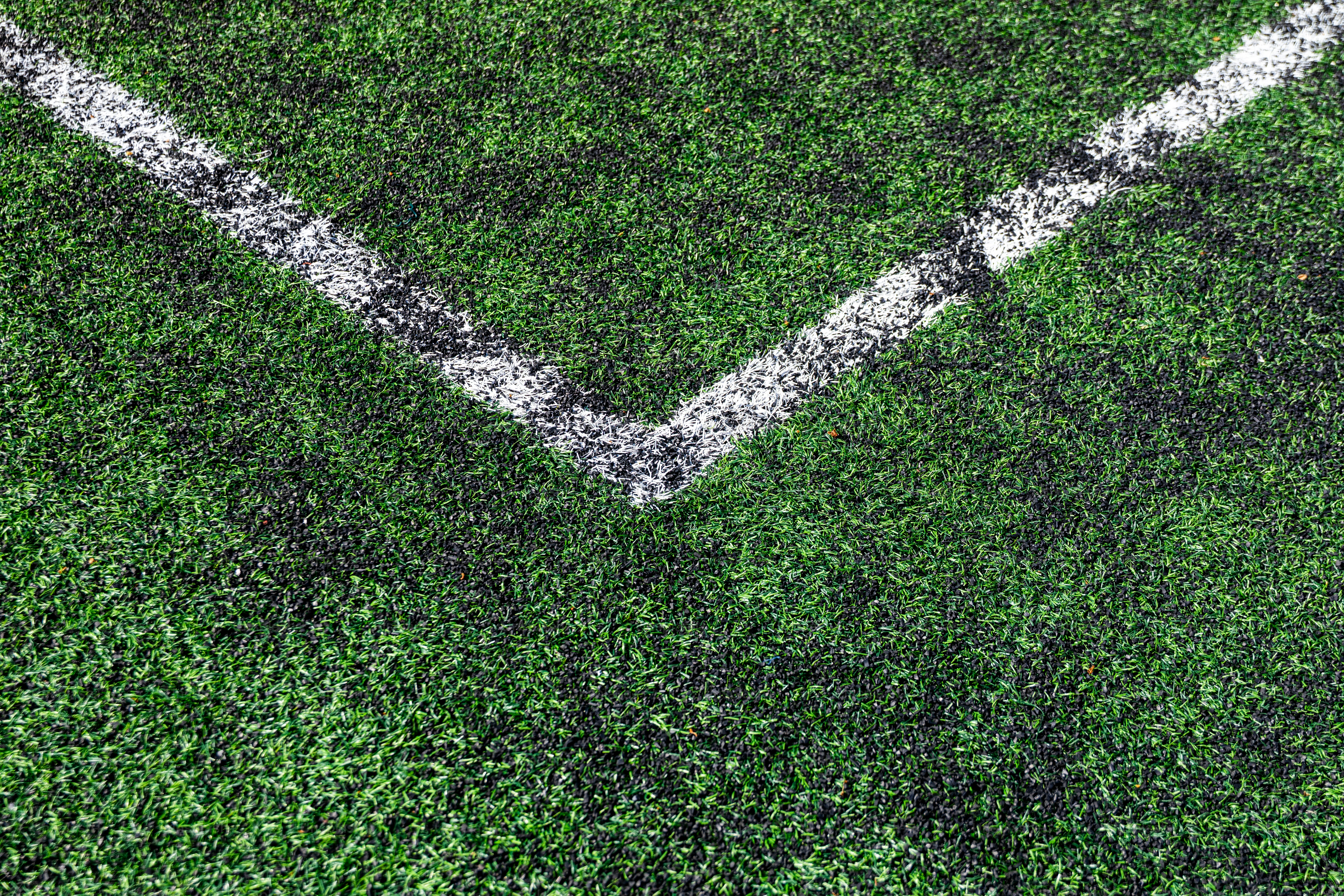 Nahaufnahme eines grünen Fußballfeldes mit weißen Linien.