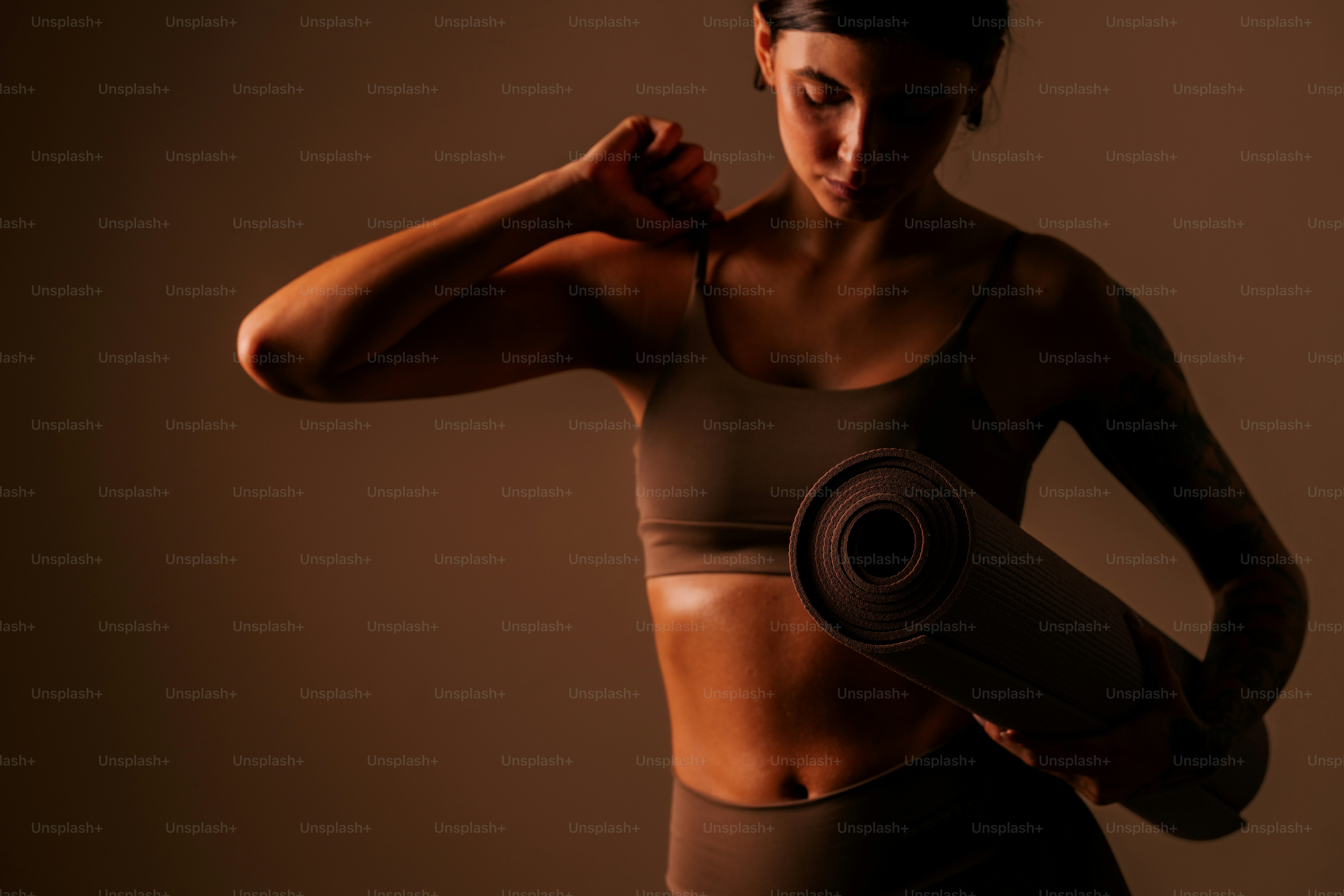 Woman in workout clothes holding a yoga mat