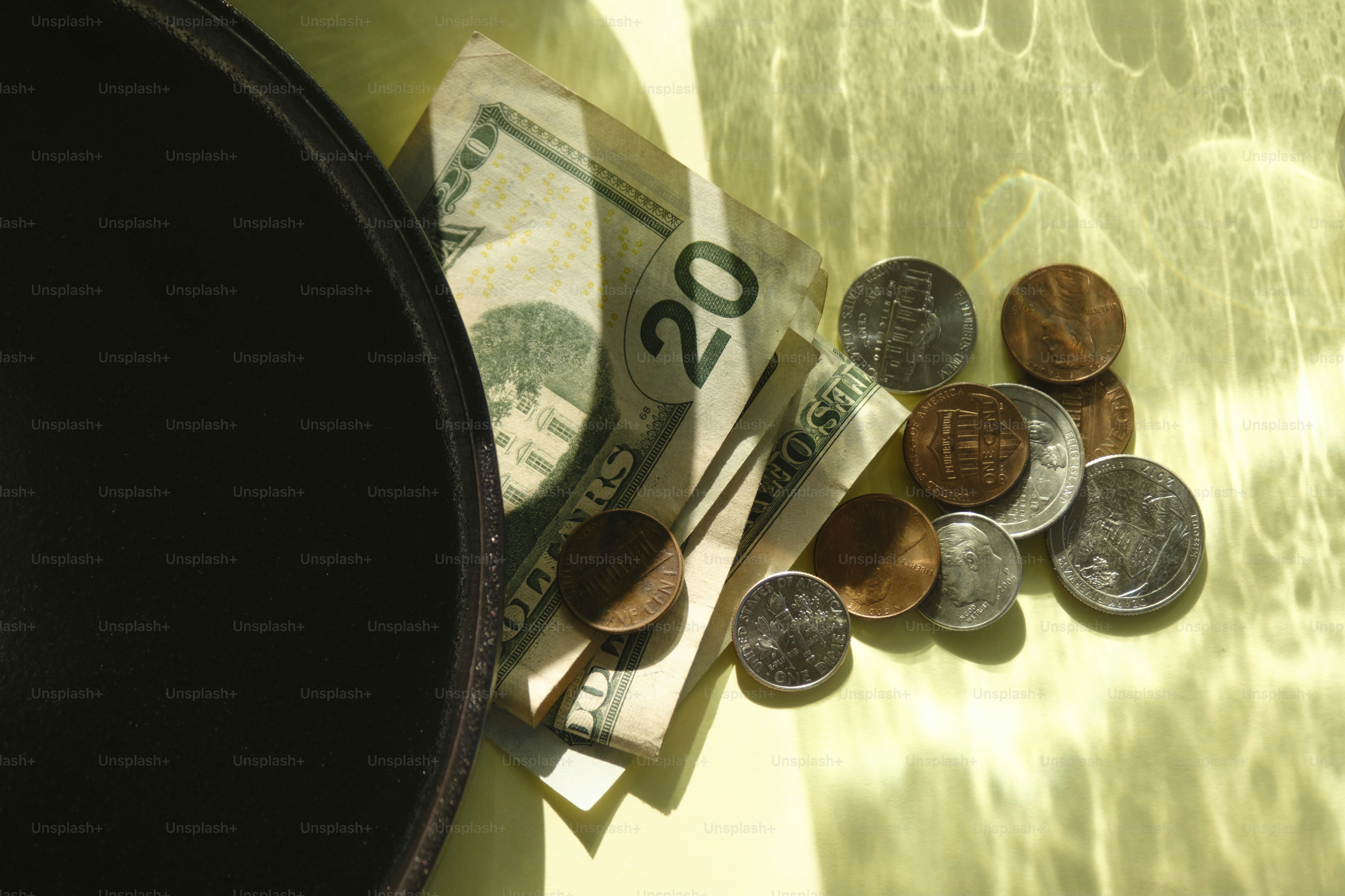 US-Dollar-Scheine und Münzen neben einer dunklen Schale.