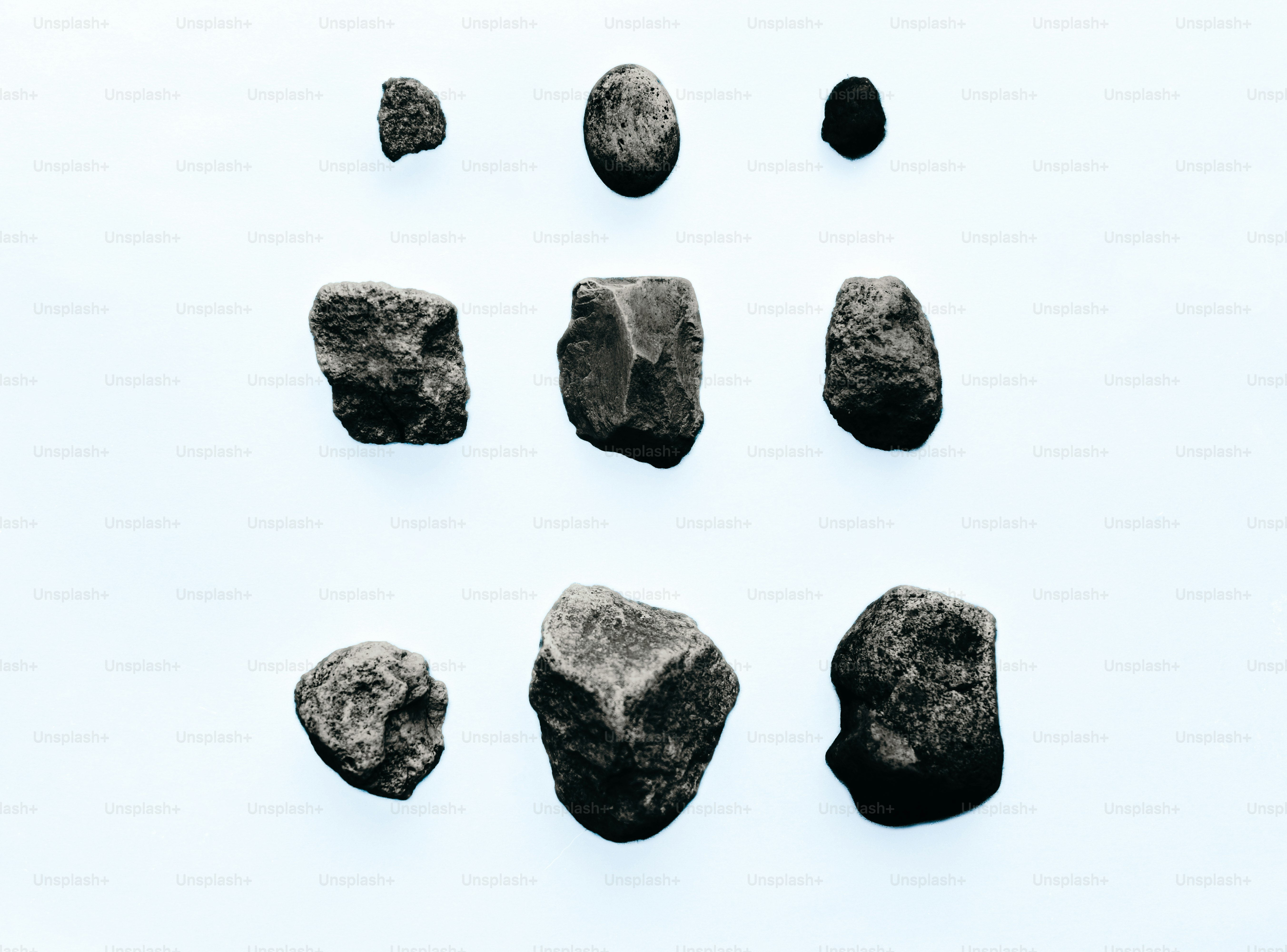 Nine various sized stones on a light blue background.