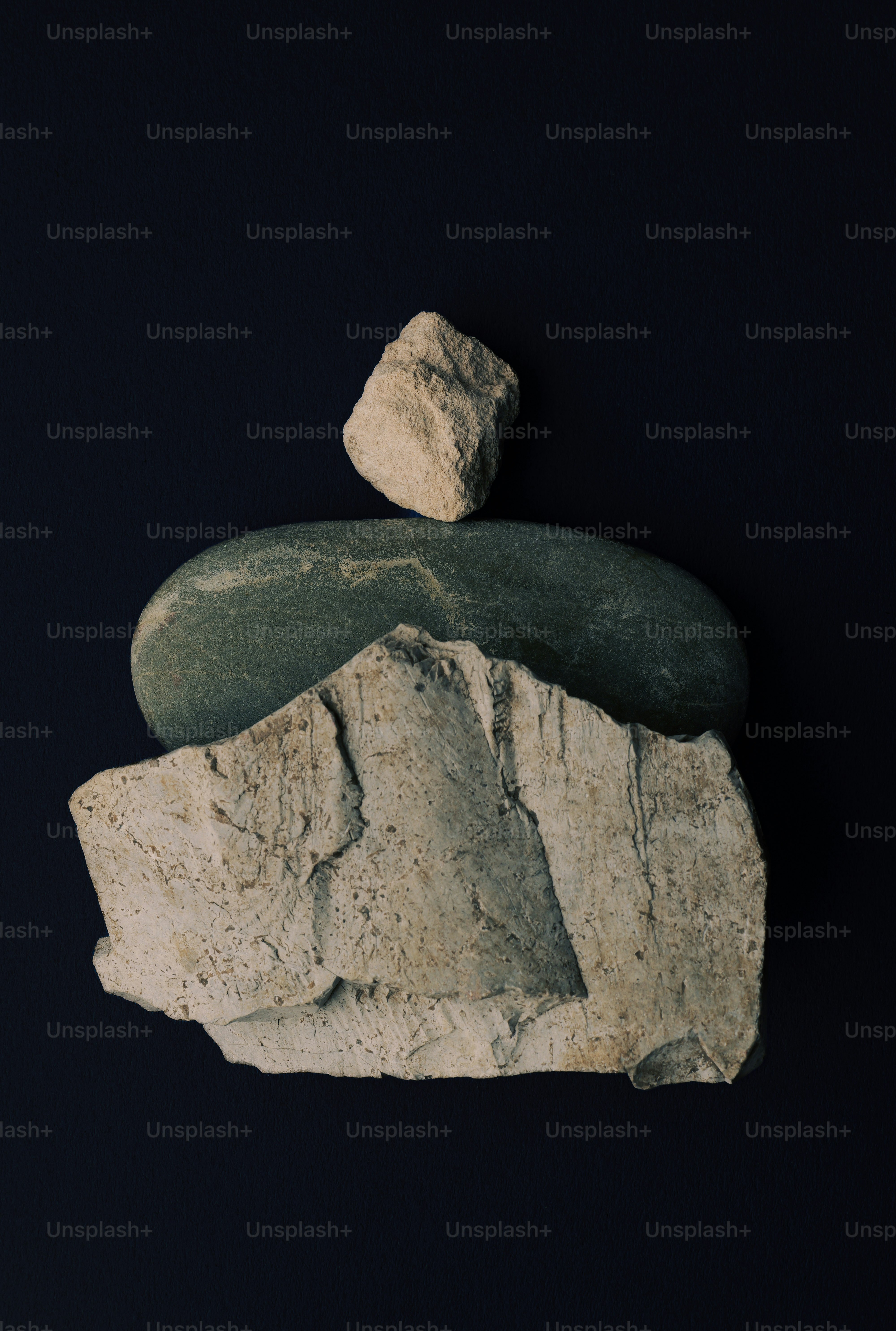 Three balanced rocks on a dark background