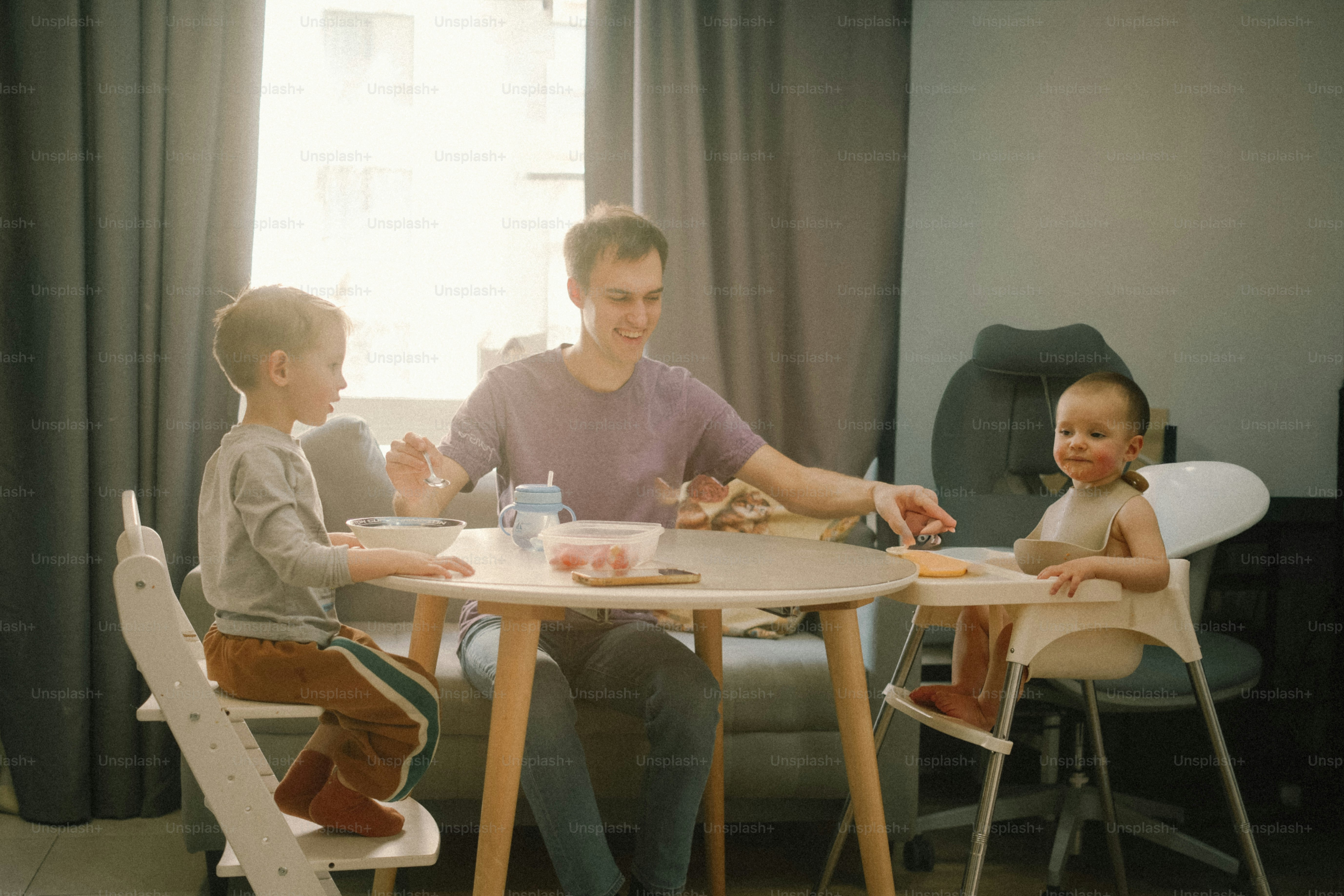 Padre e due figli che mangiano a un tavolo rotondo.