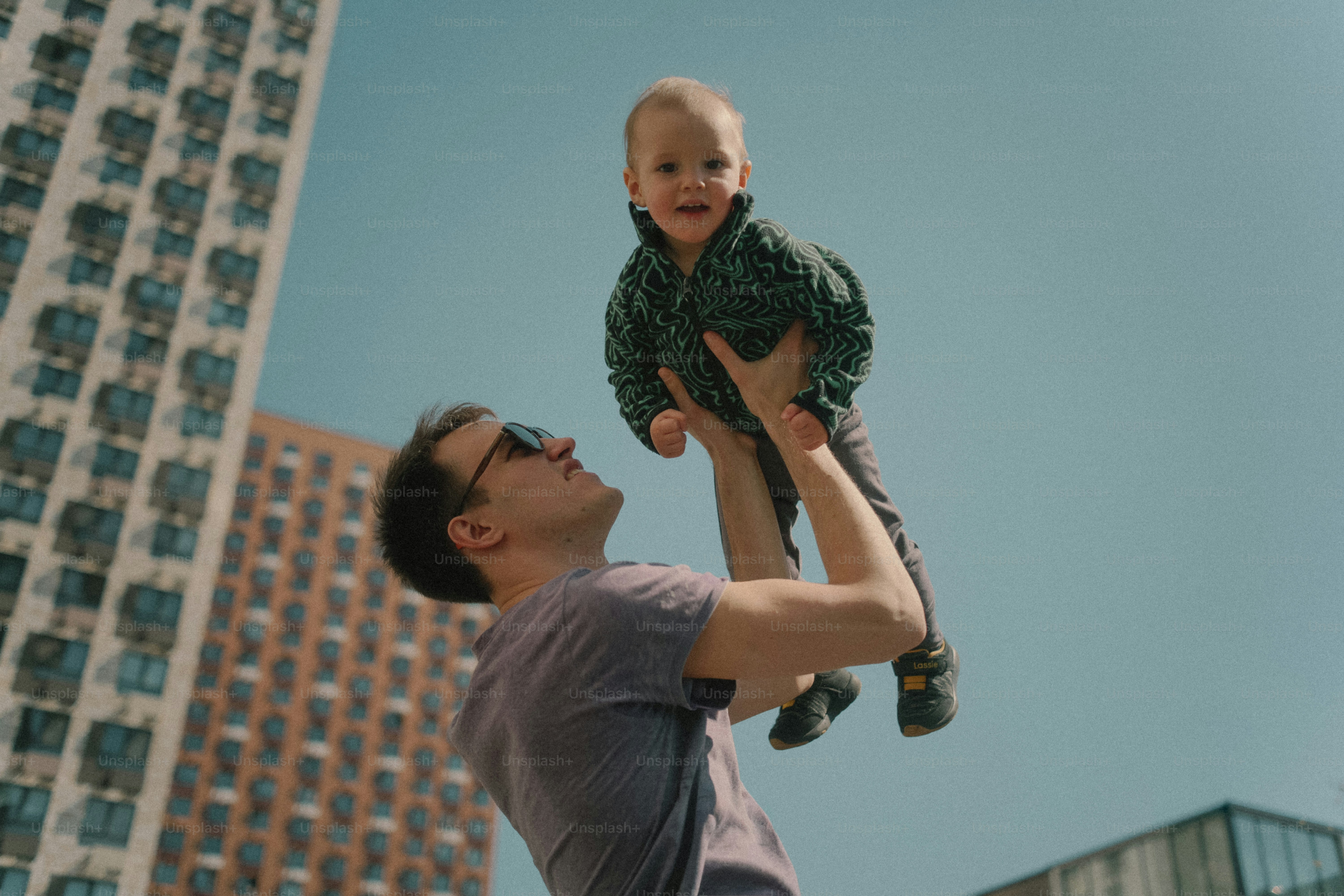 Padre che tiene in alto il suo bambino sorridente.