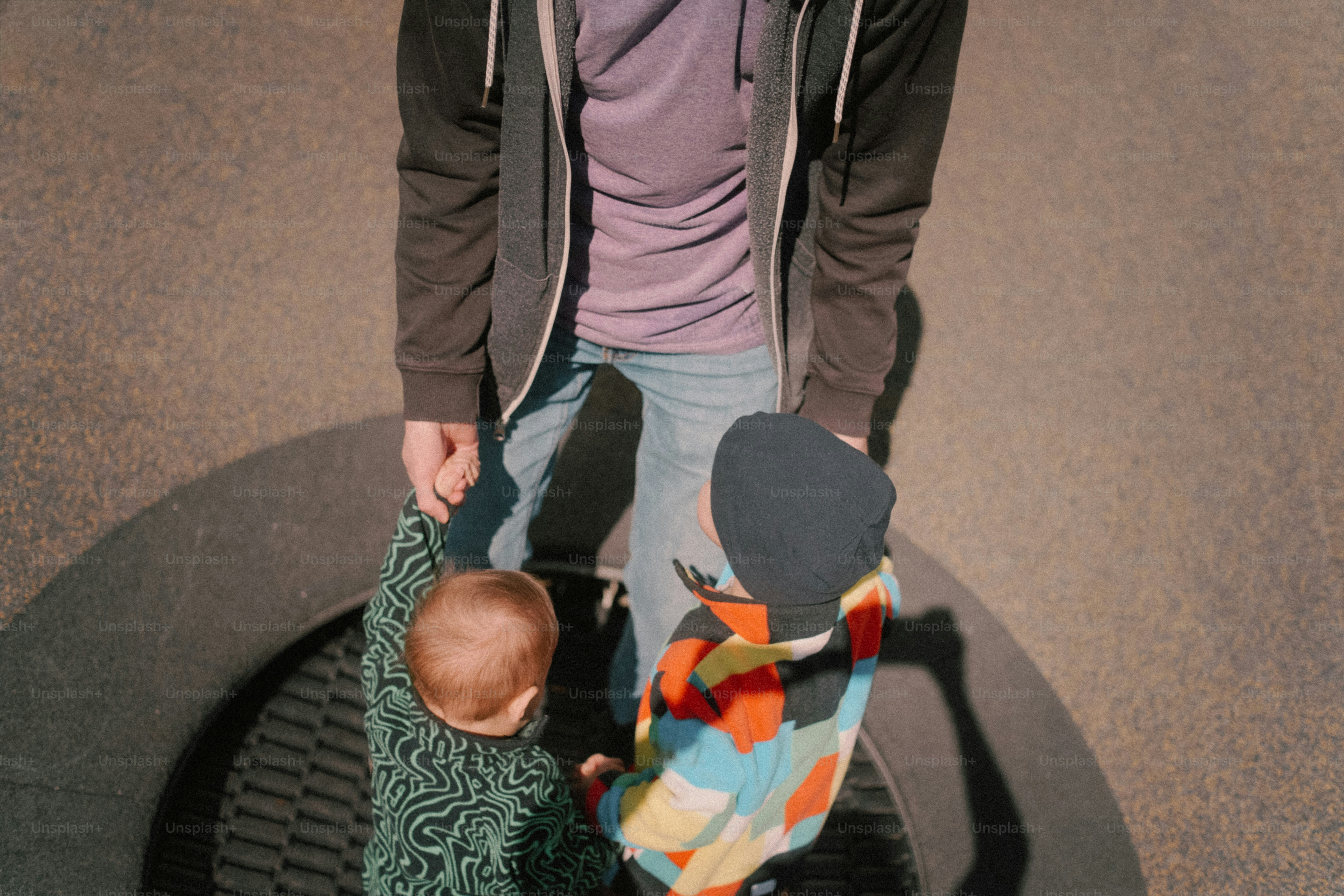 Adulto con due bambini piccoli su una superficie circolare.
