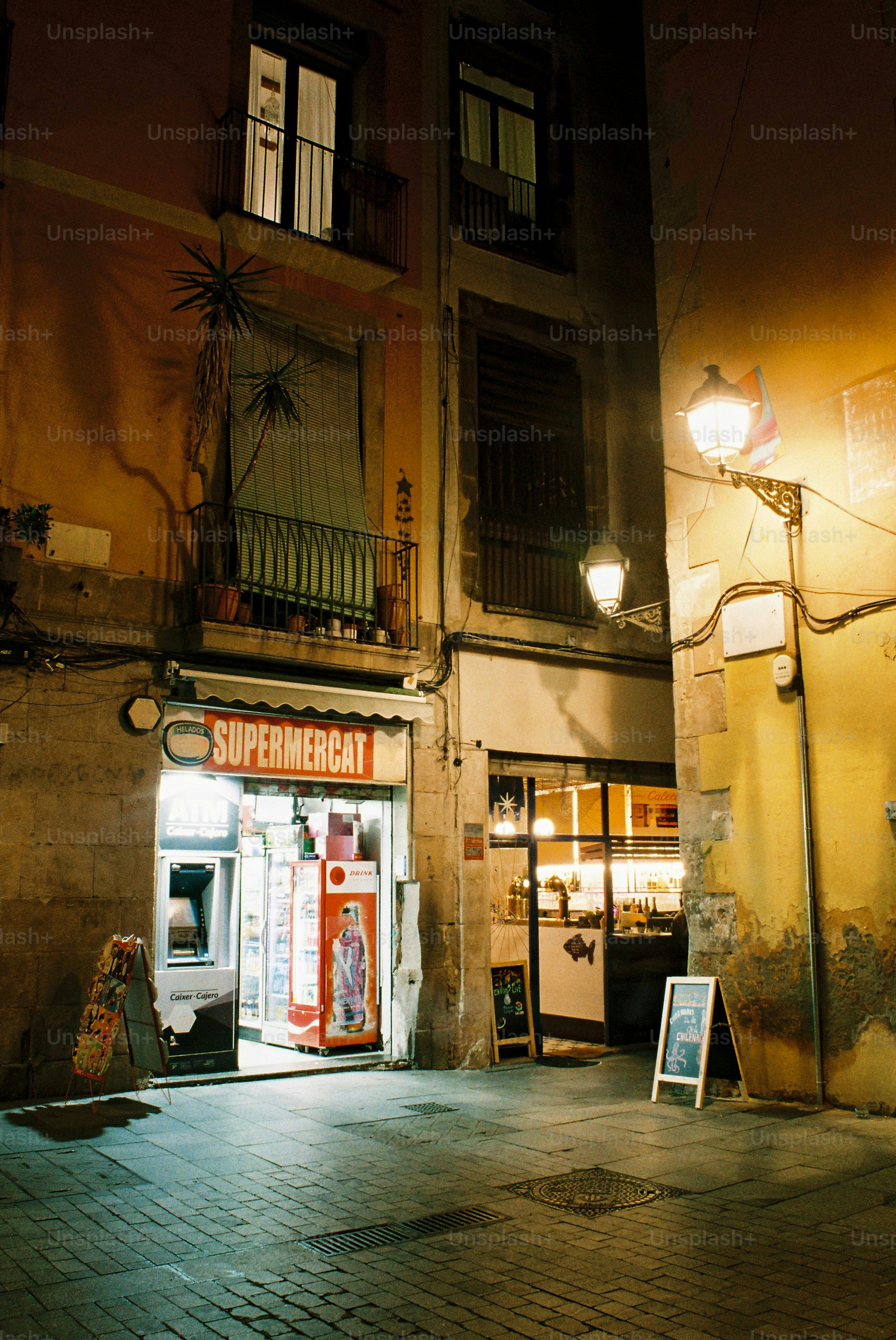 A dimly lit street with a supermarket at night.