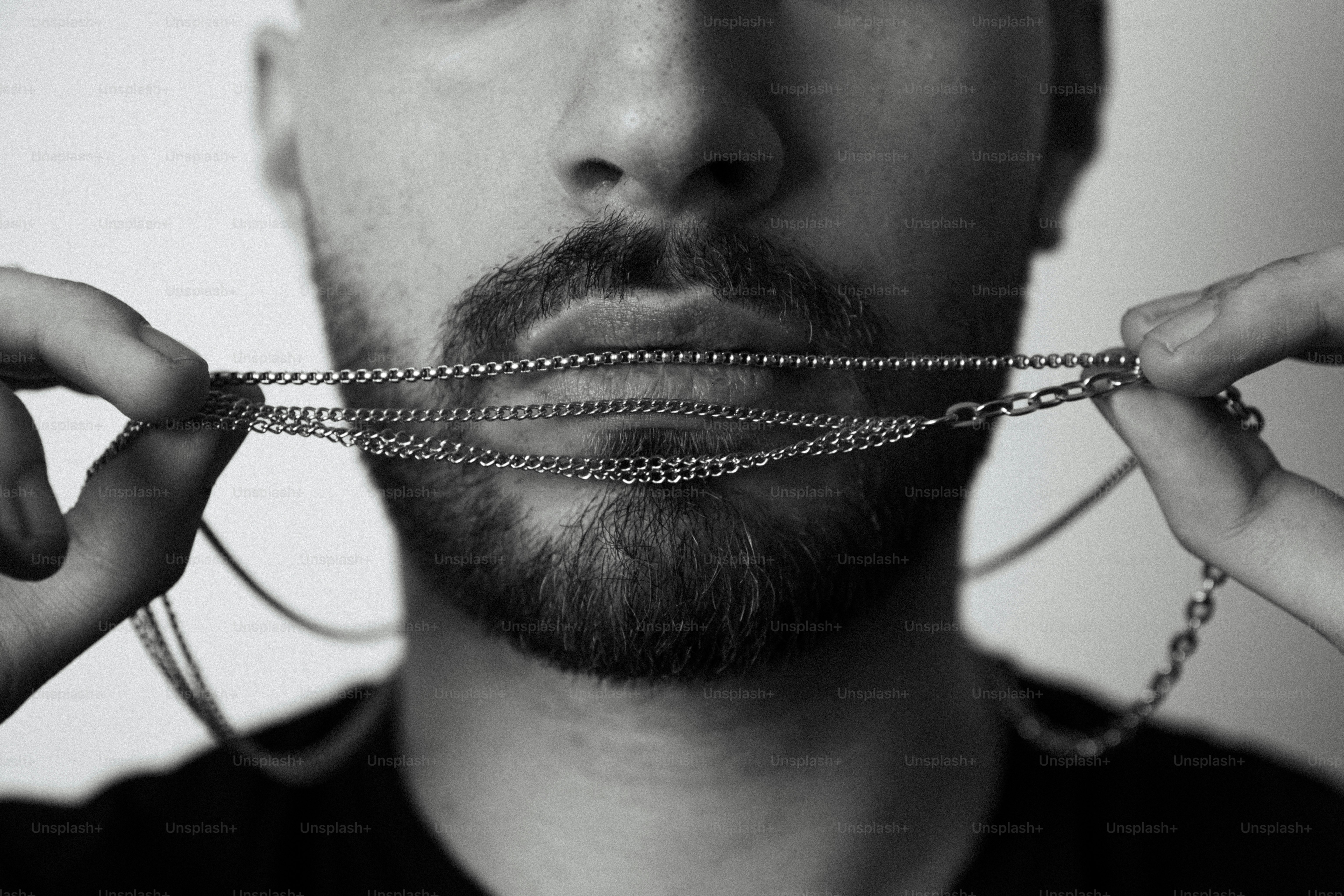 Bärtiger Mann hält eine silberne Kette über die Lippen.