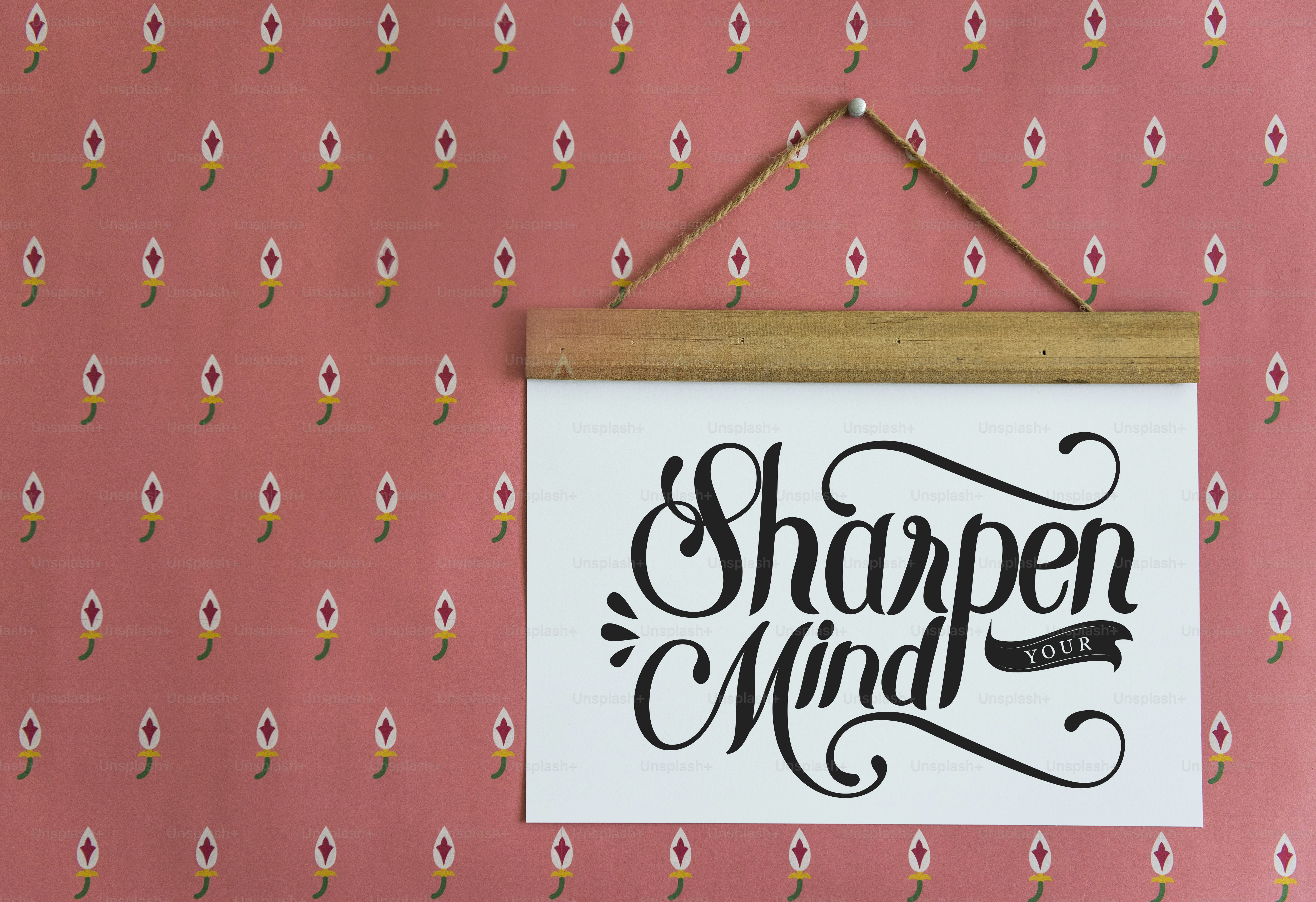 ピンクの花柄の壁に「Sharpen Your Mind」と書かれた看板が吊るされている