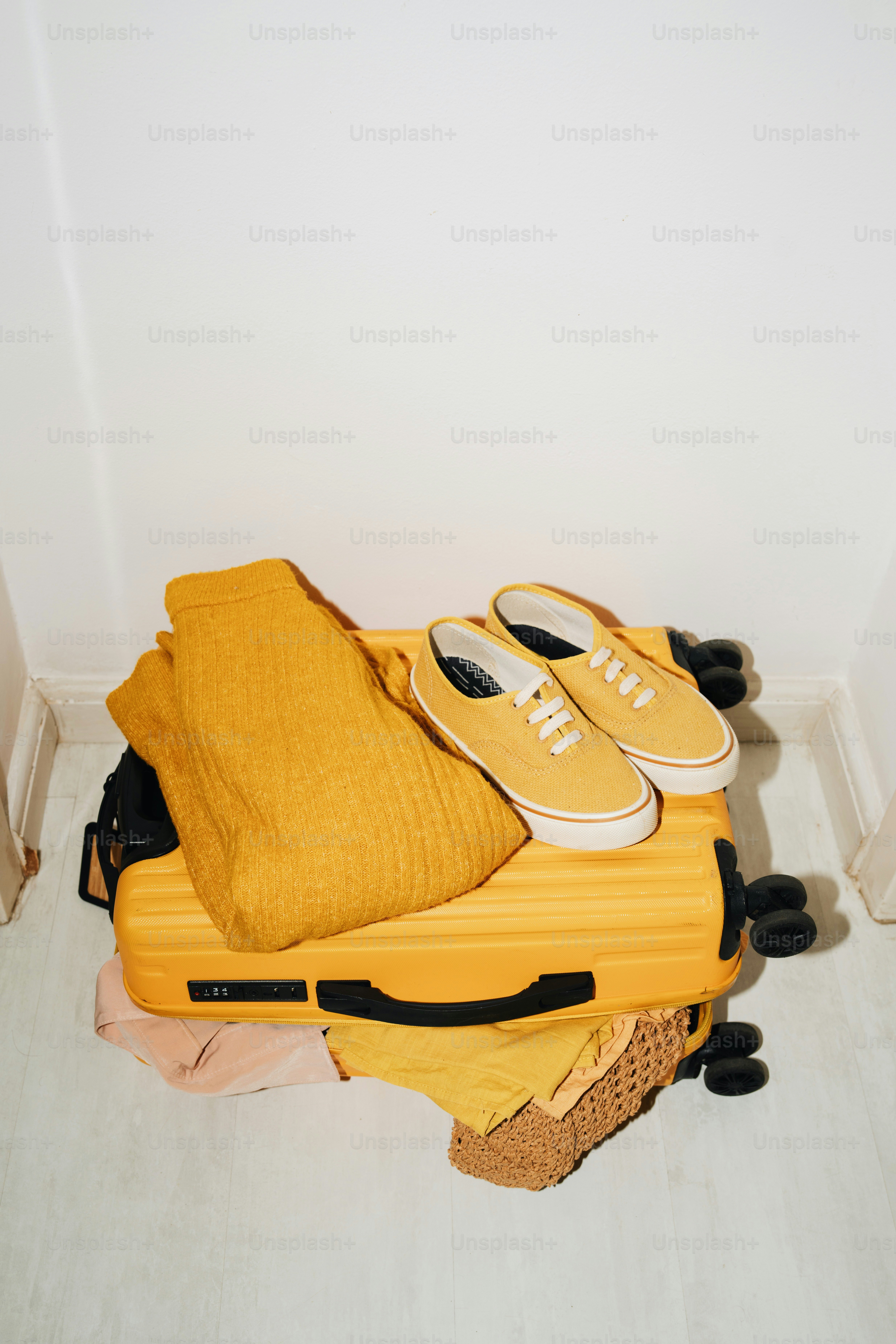 Yellow suitcase packed with clothes and shoes.