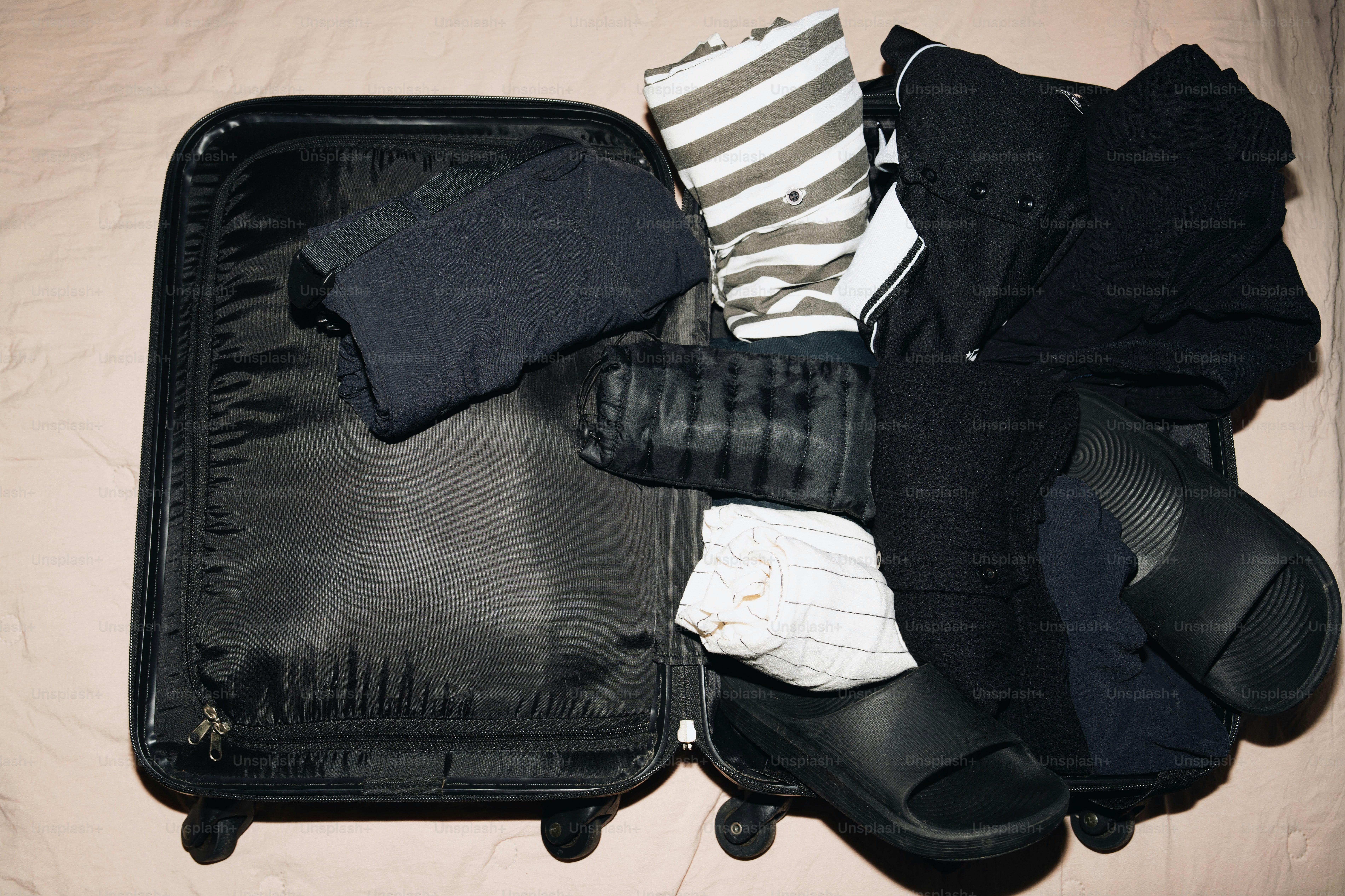 Clothes and sandals packed into an open suitcase.