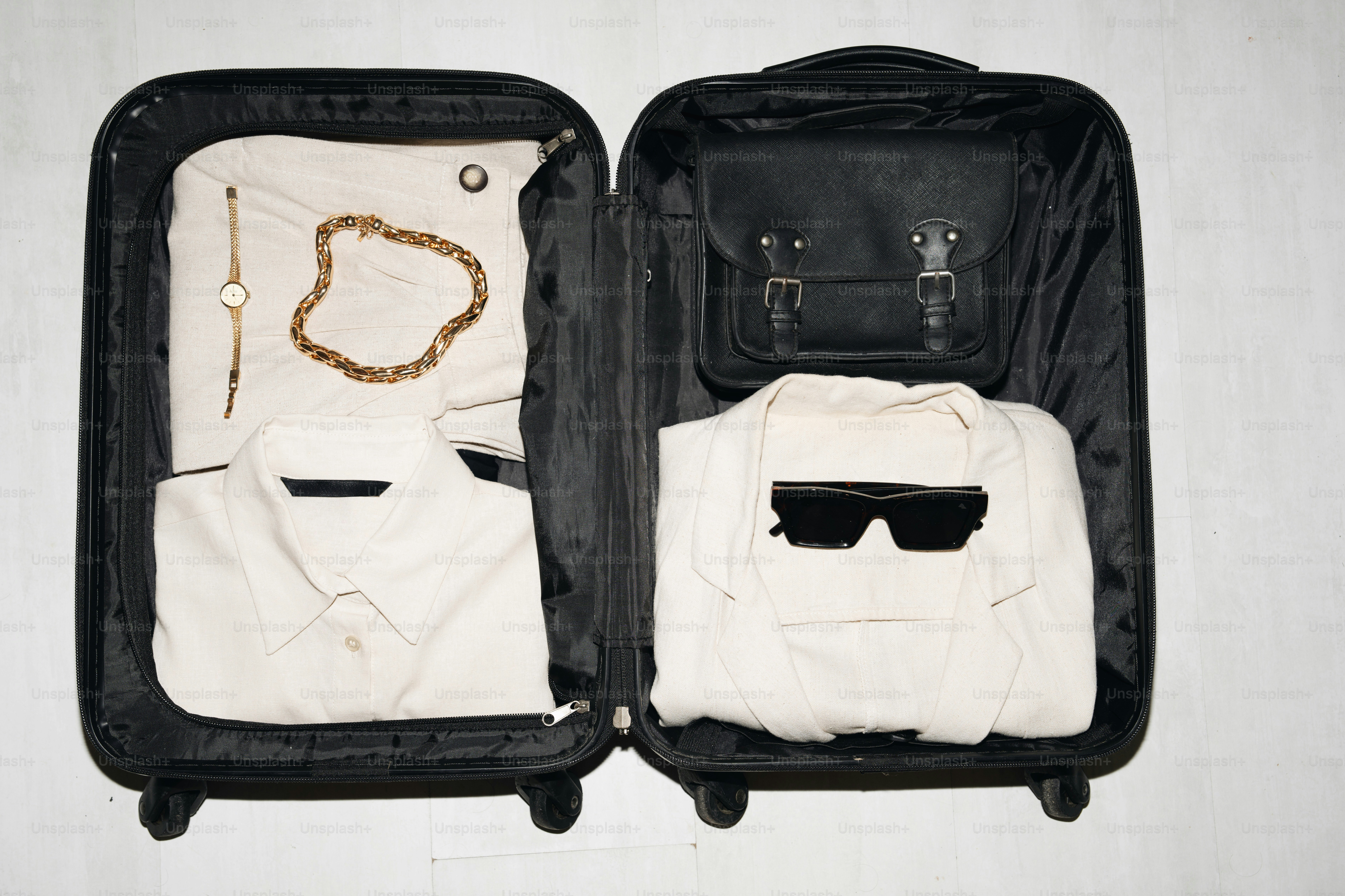 Open suitcase packed with clothes and accessories.
