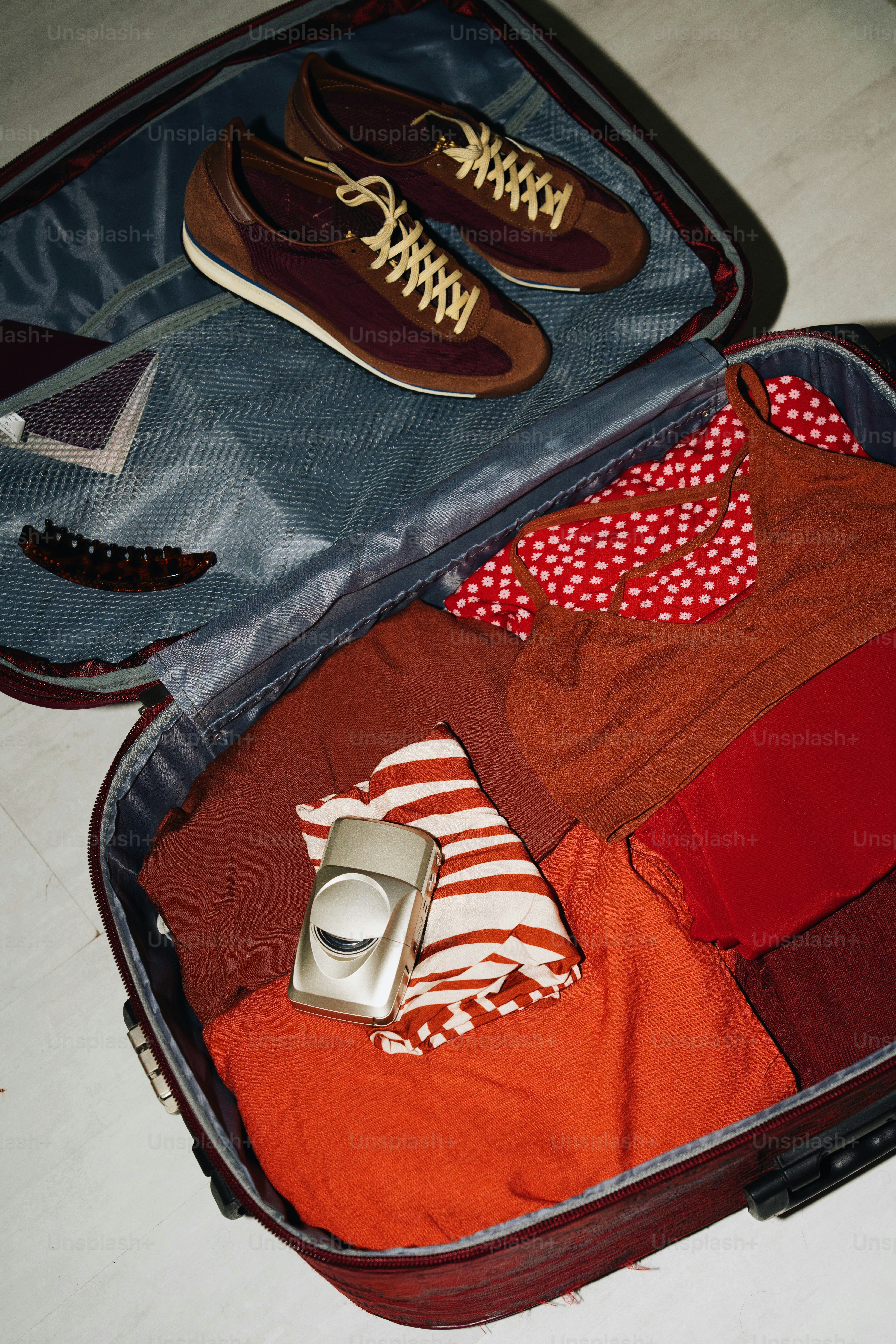 Open suitcase packed with clothes and shoes.
