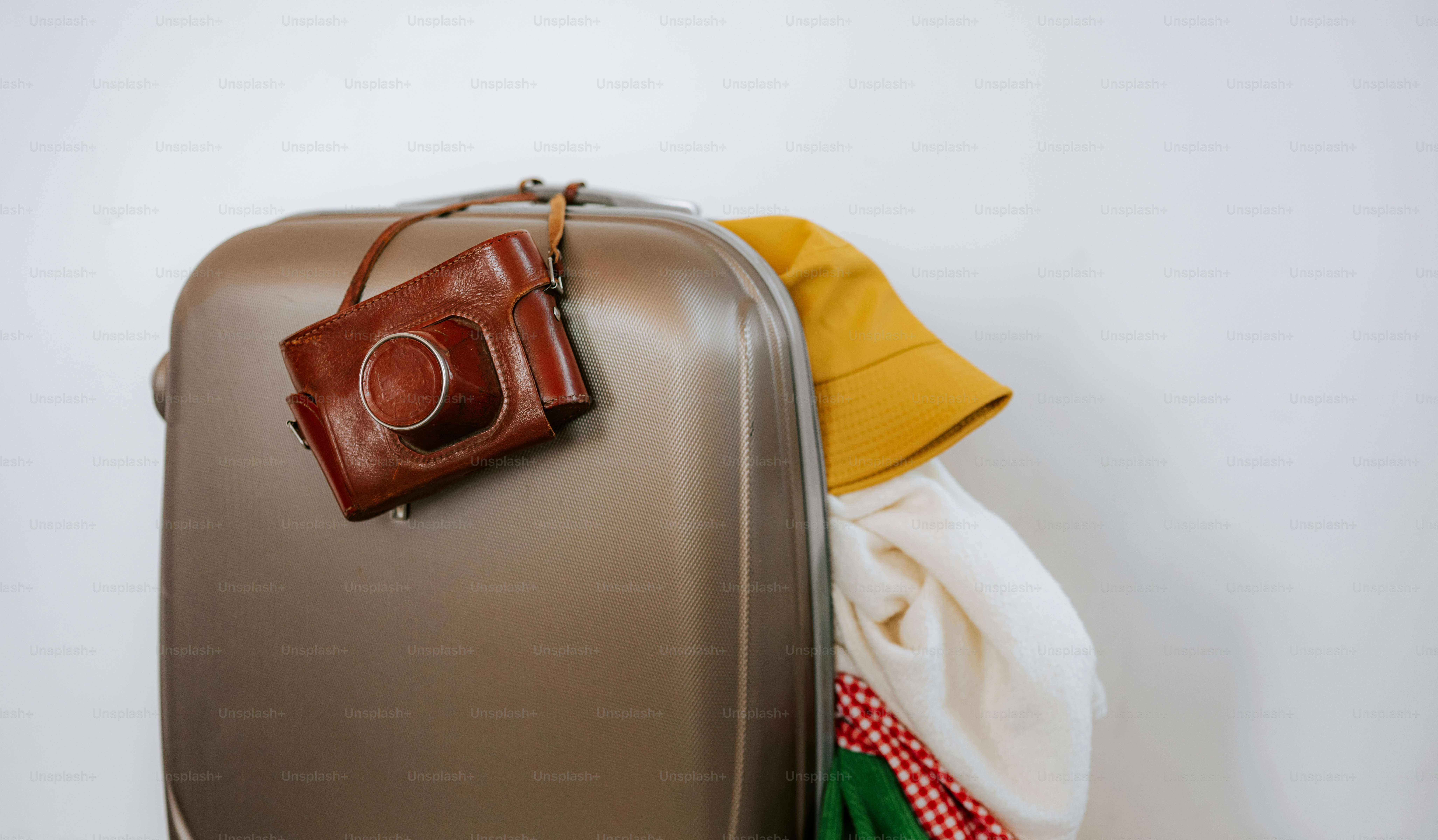A suitcase packed with clothes and a vintage camera.