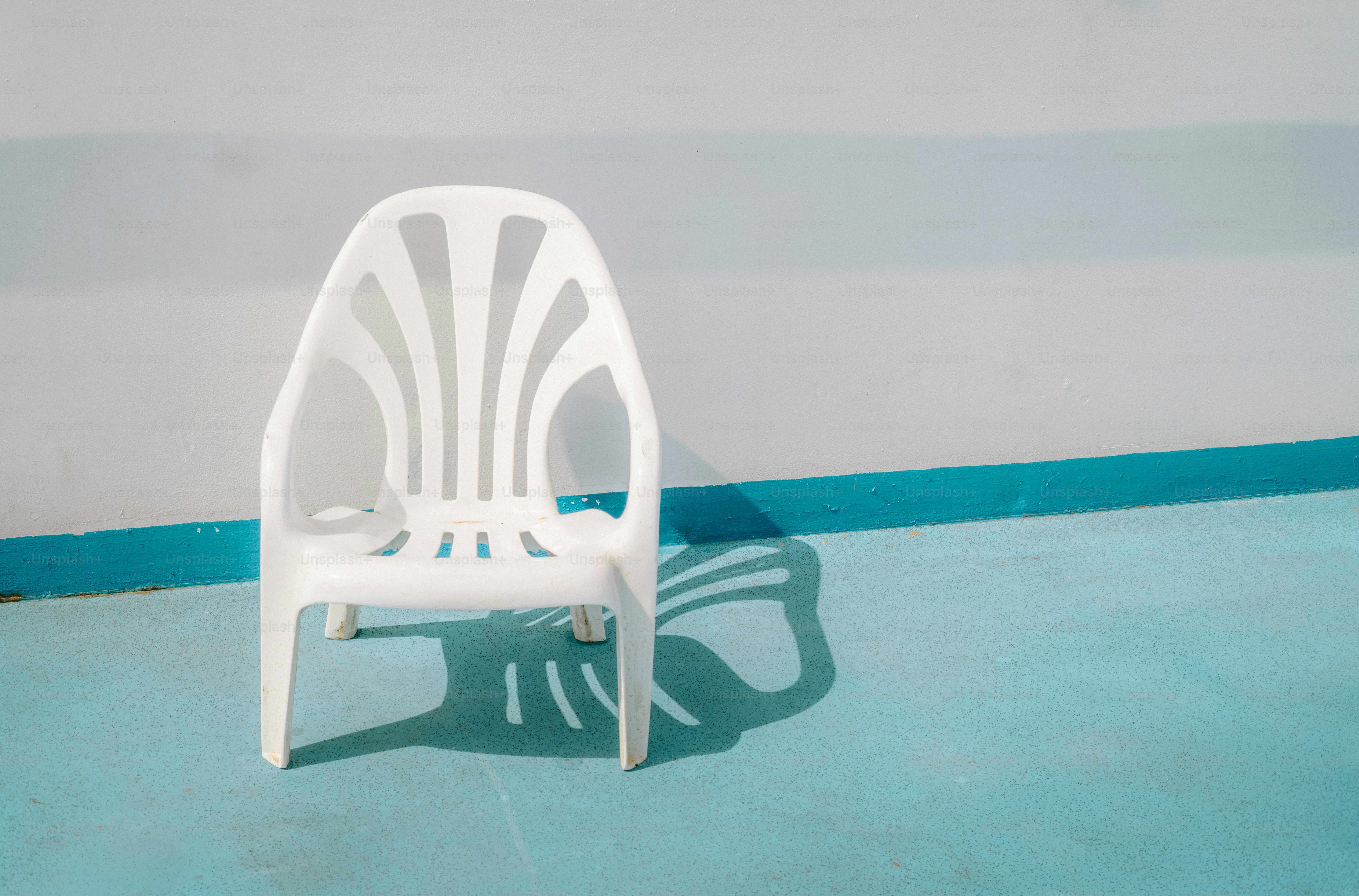 Ein weißer Plastikstuhl wirft einen Schatten auf den Boden