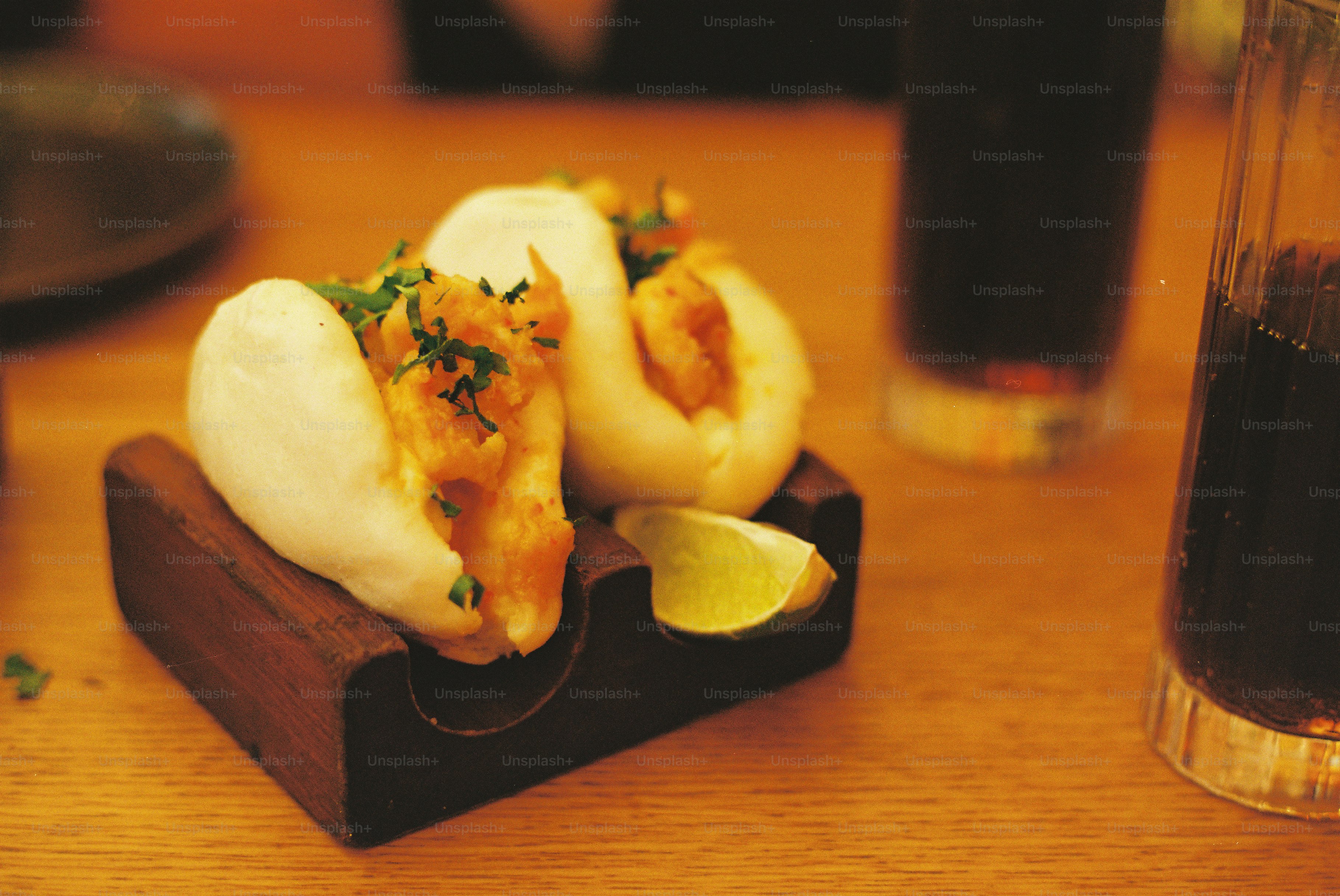 Two bao buns with filling and lime on wooden stand