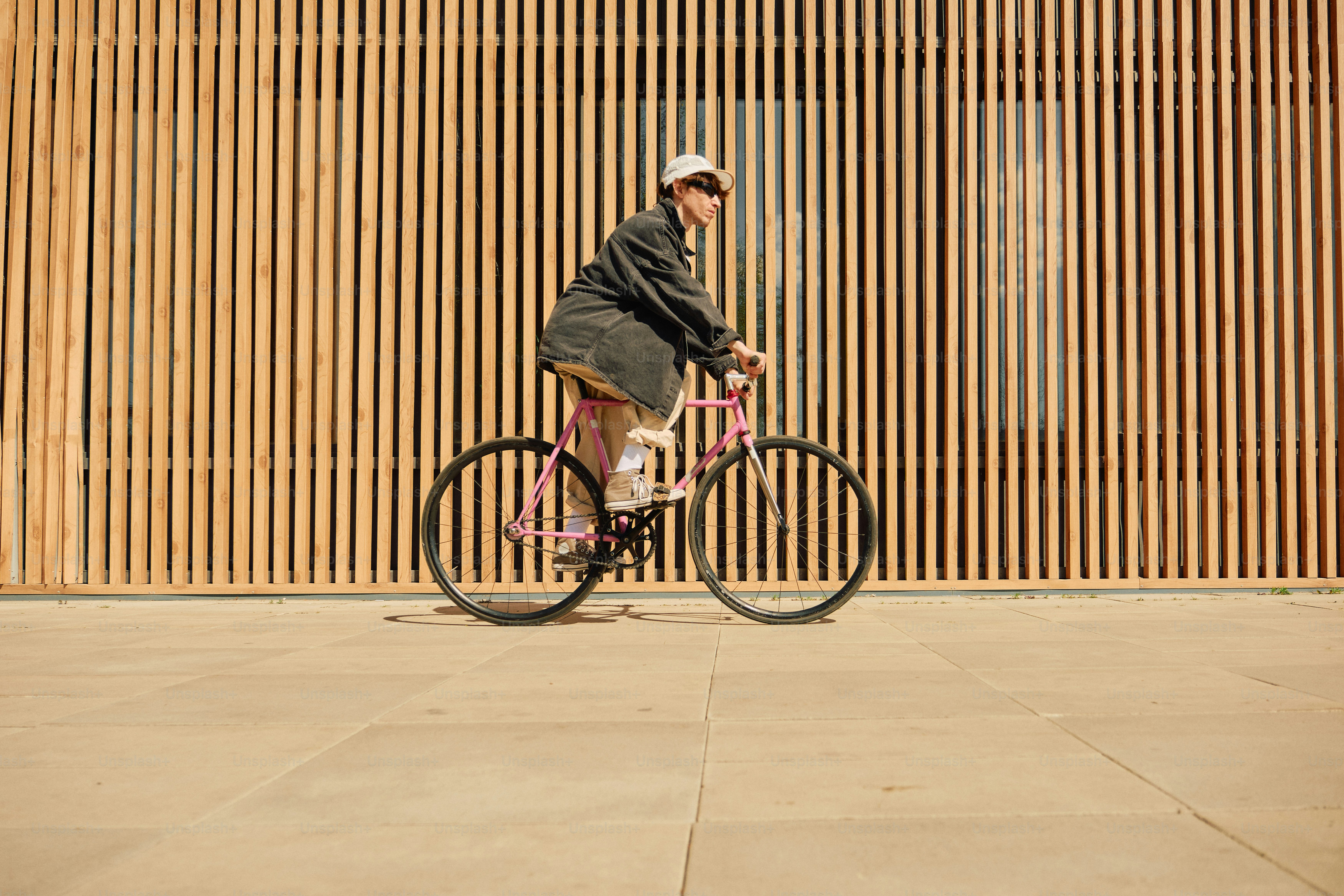 Person riding a bicycle in front of a wooden wall