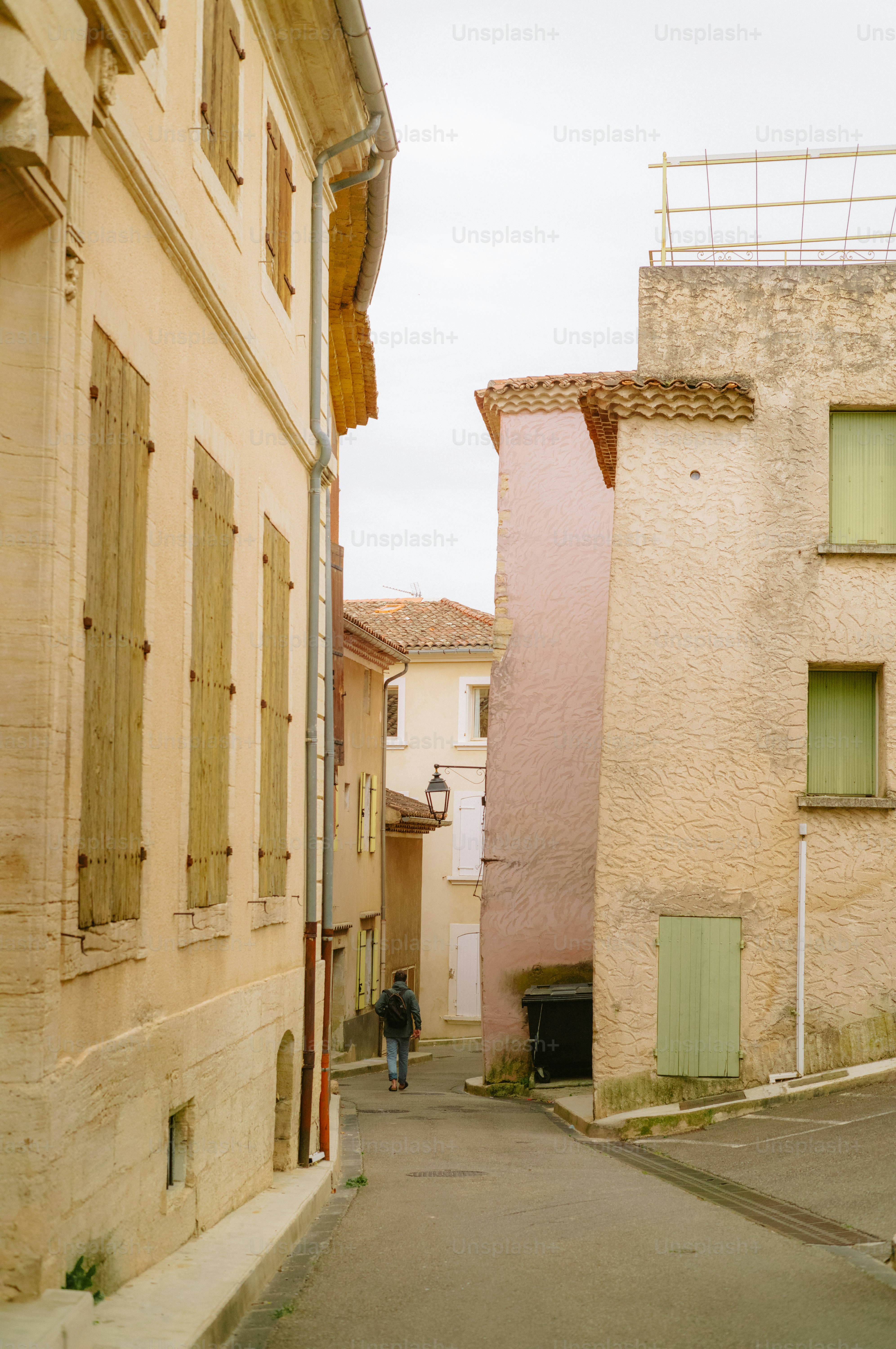 A man walks down a narrow street between buildings.