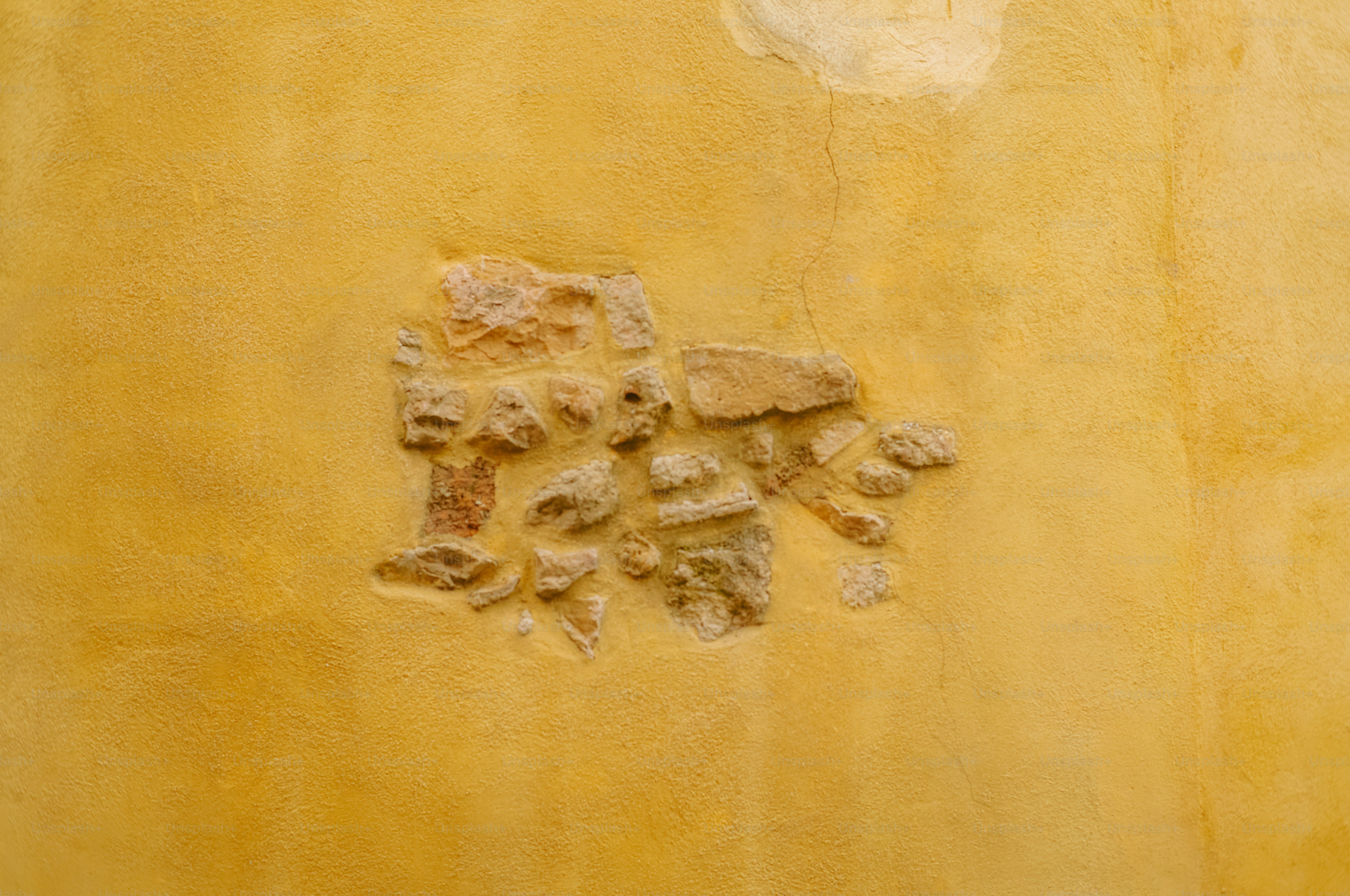 Rough textured yellow wall with small stones embedded stones