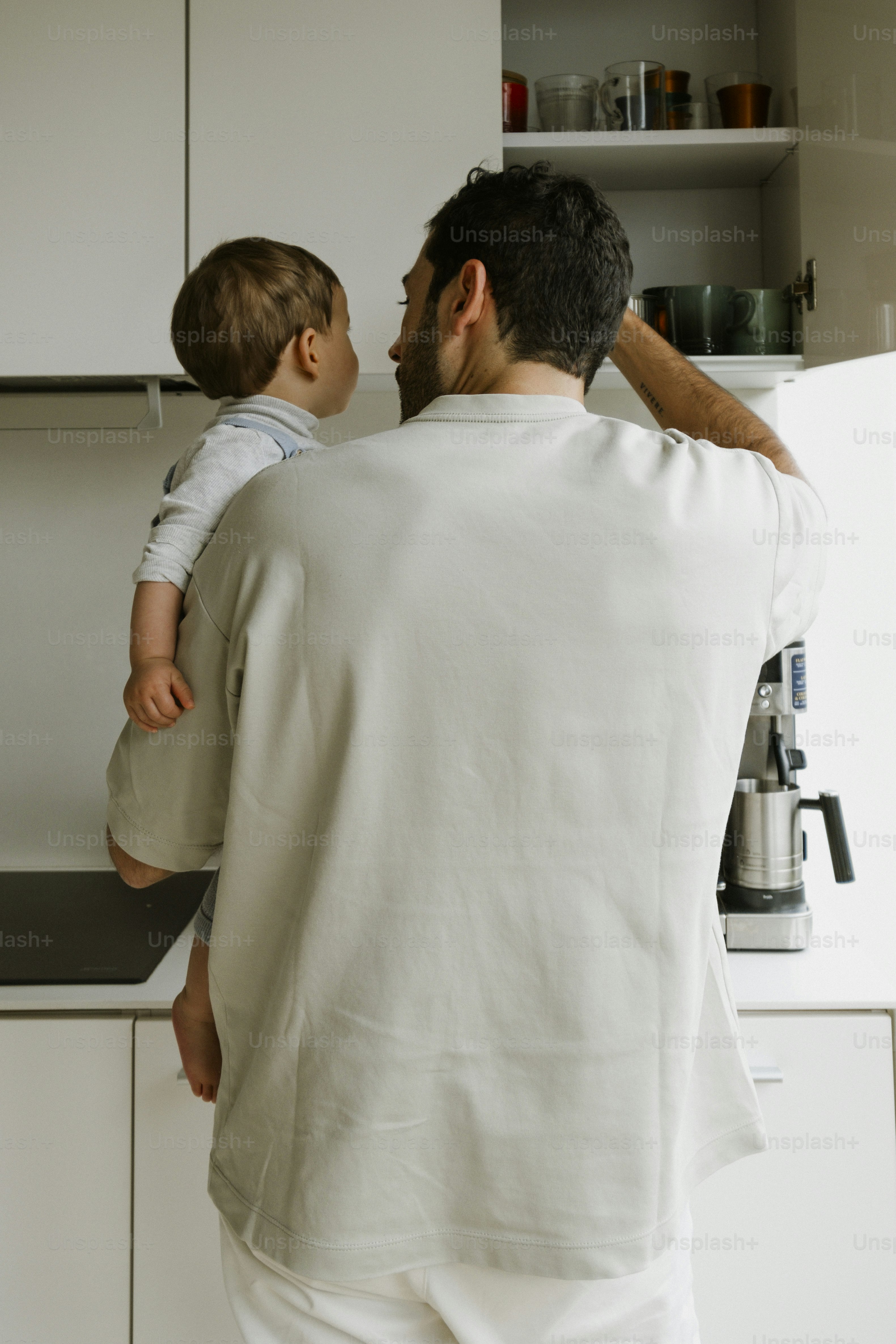 Father holding his child in a modern kitchen.