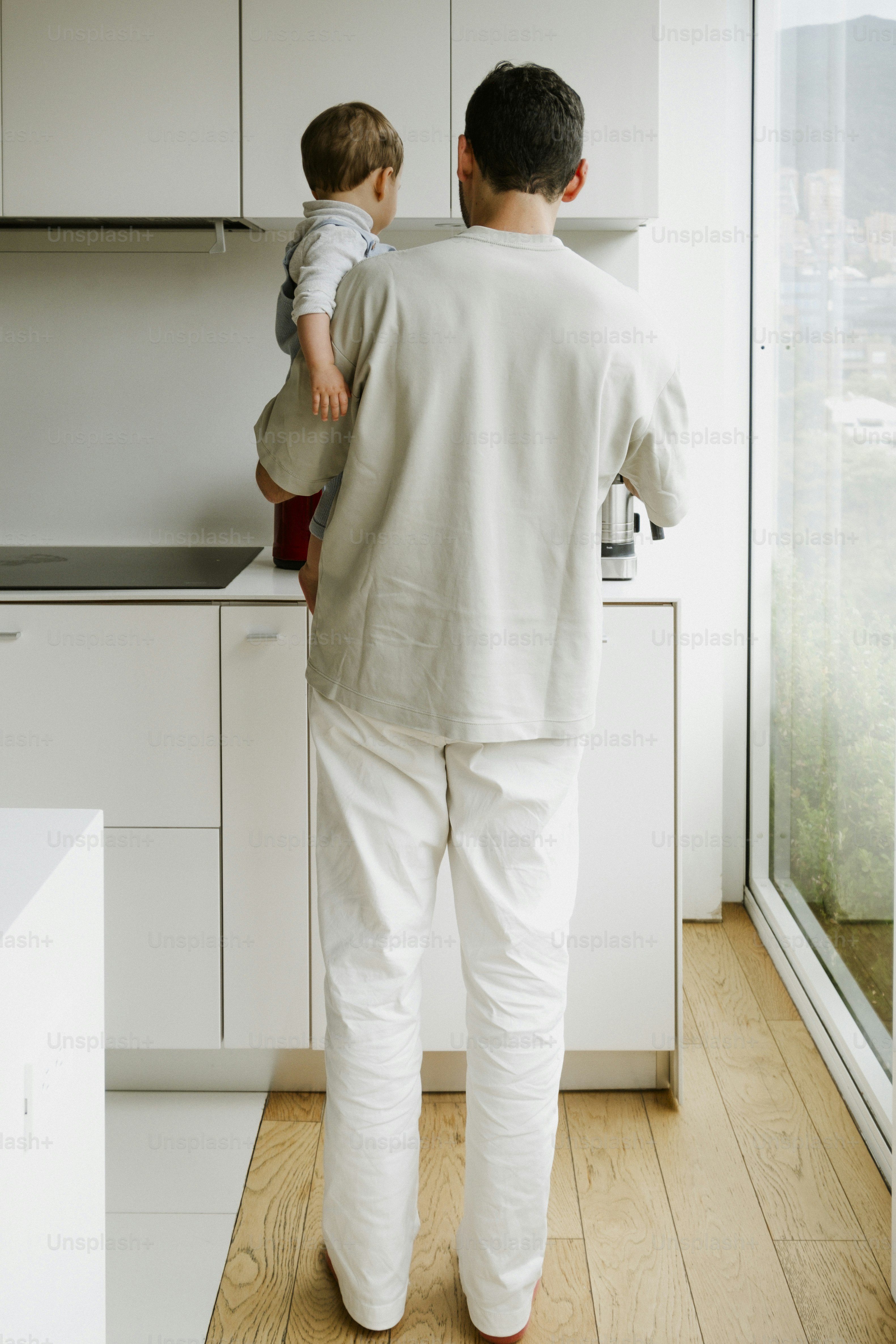 Father holding a baby in a modern kitchen.