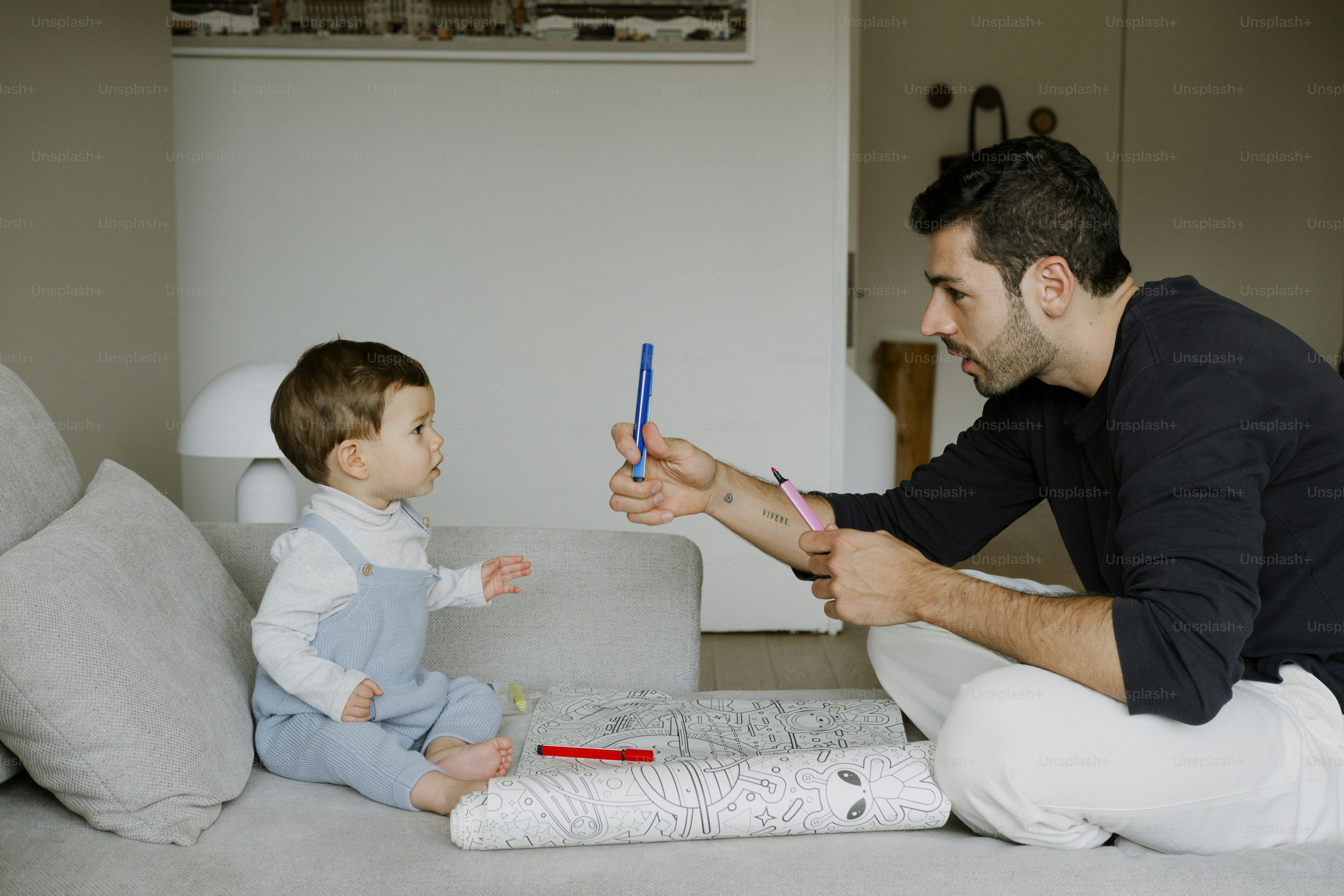 Father and baby playing with colorful pens