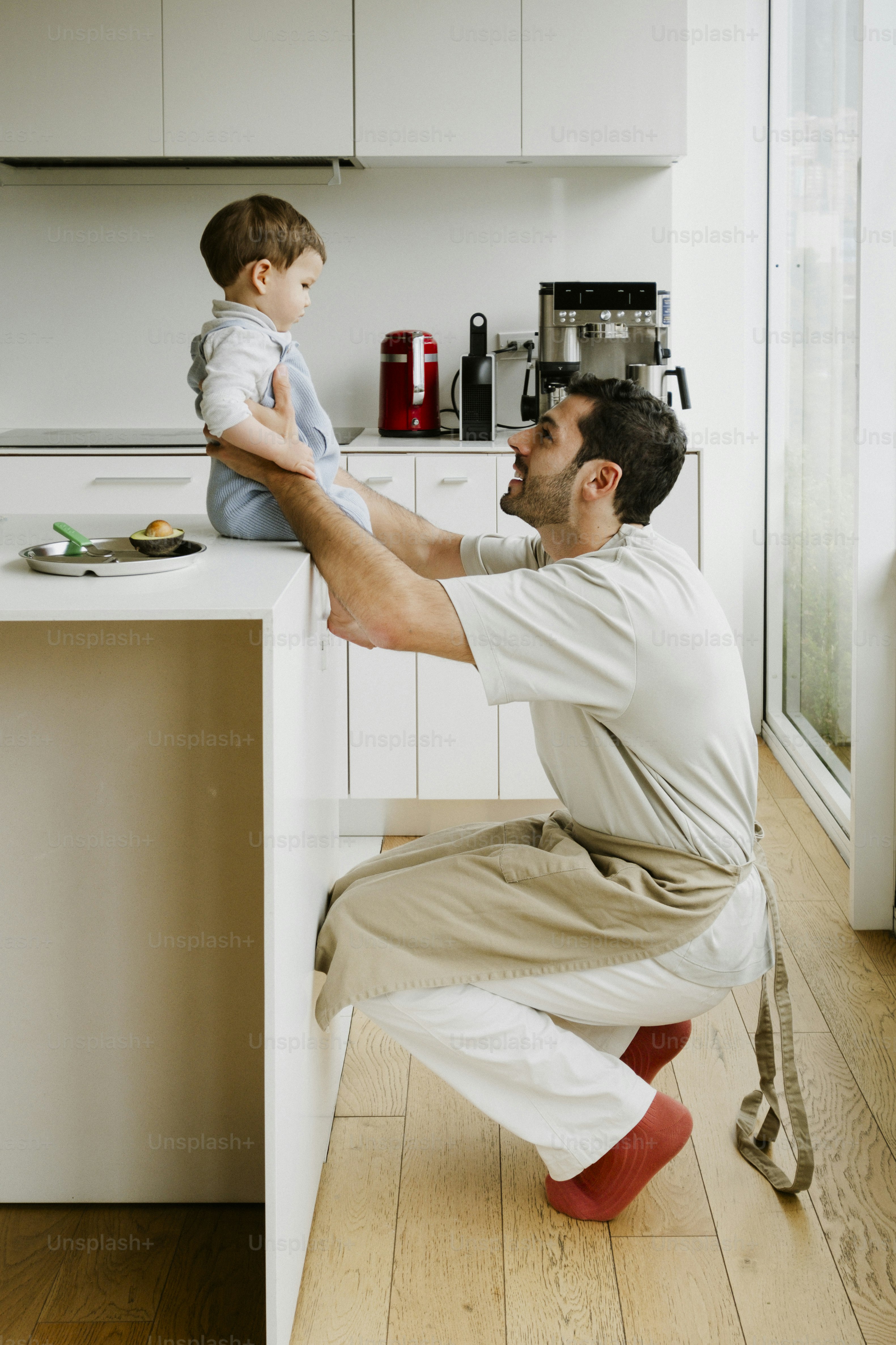 Father and son interacting in a modern kitchen.
