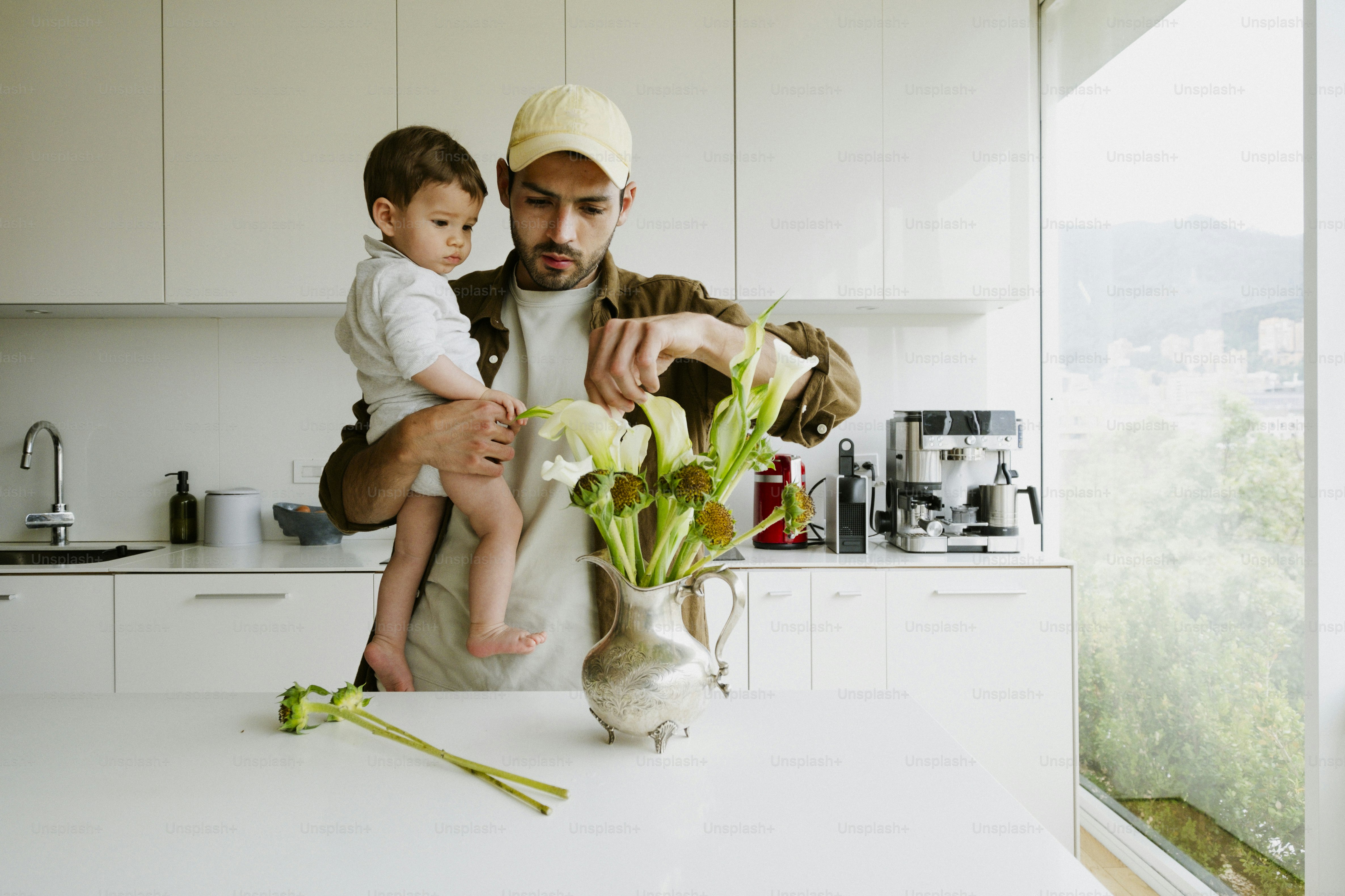 Man holding baby while arranging flowers in kitchen