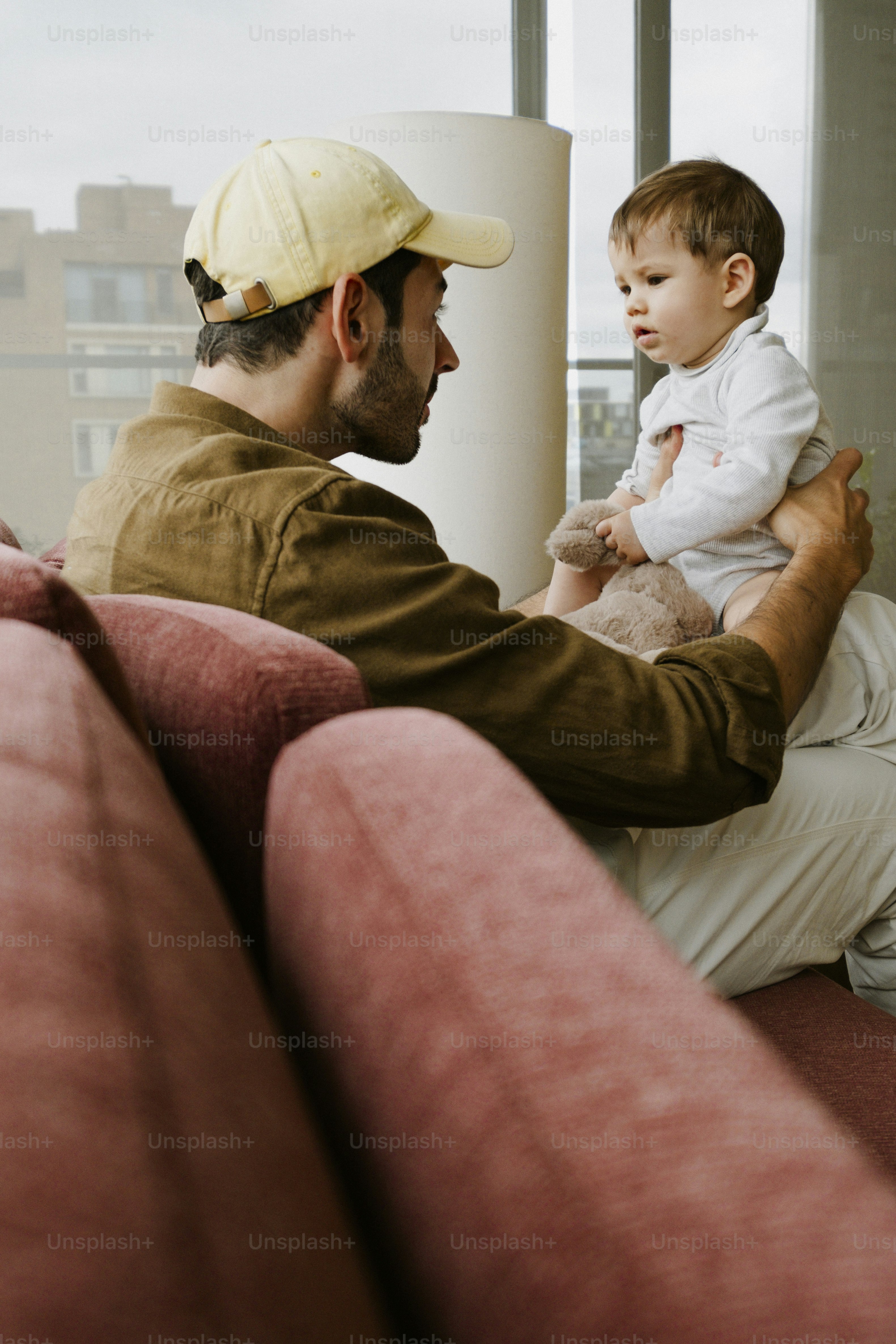 Man in a cap holding a baby on a couch