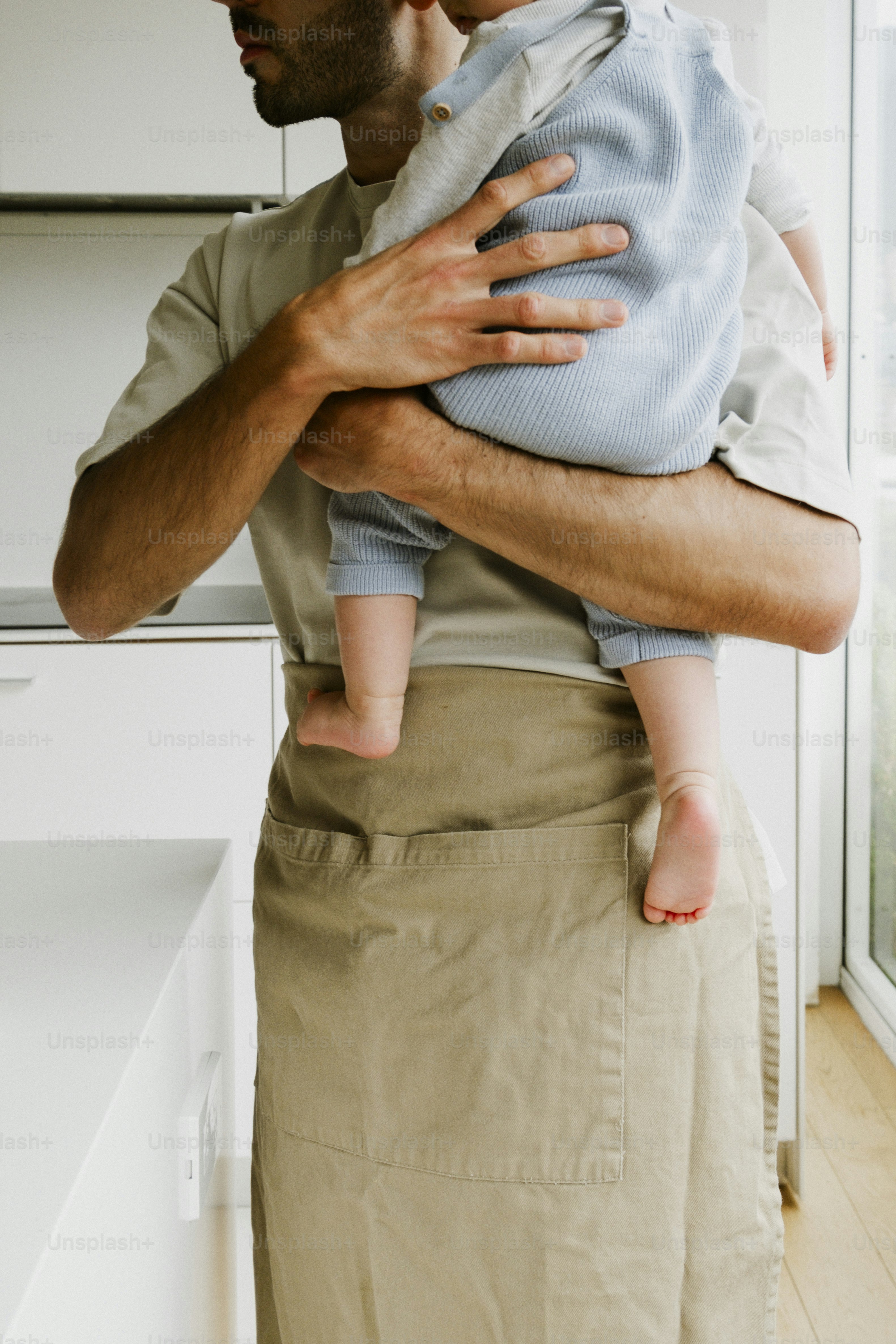 A father holding his baby in a kitchen.