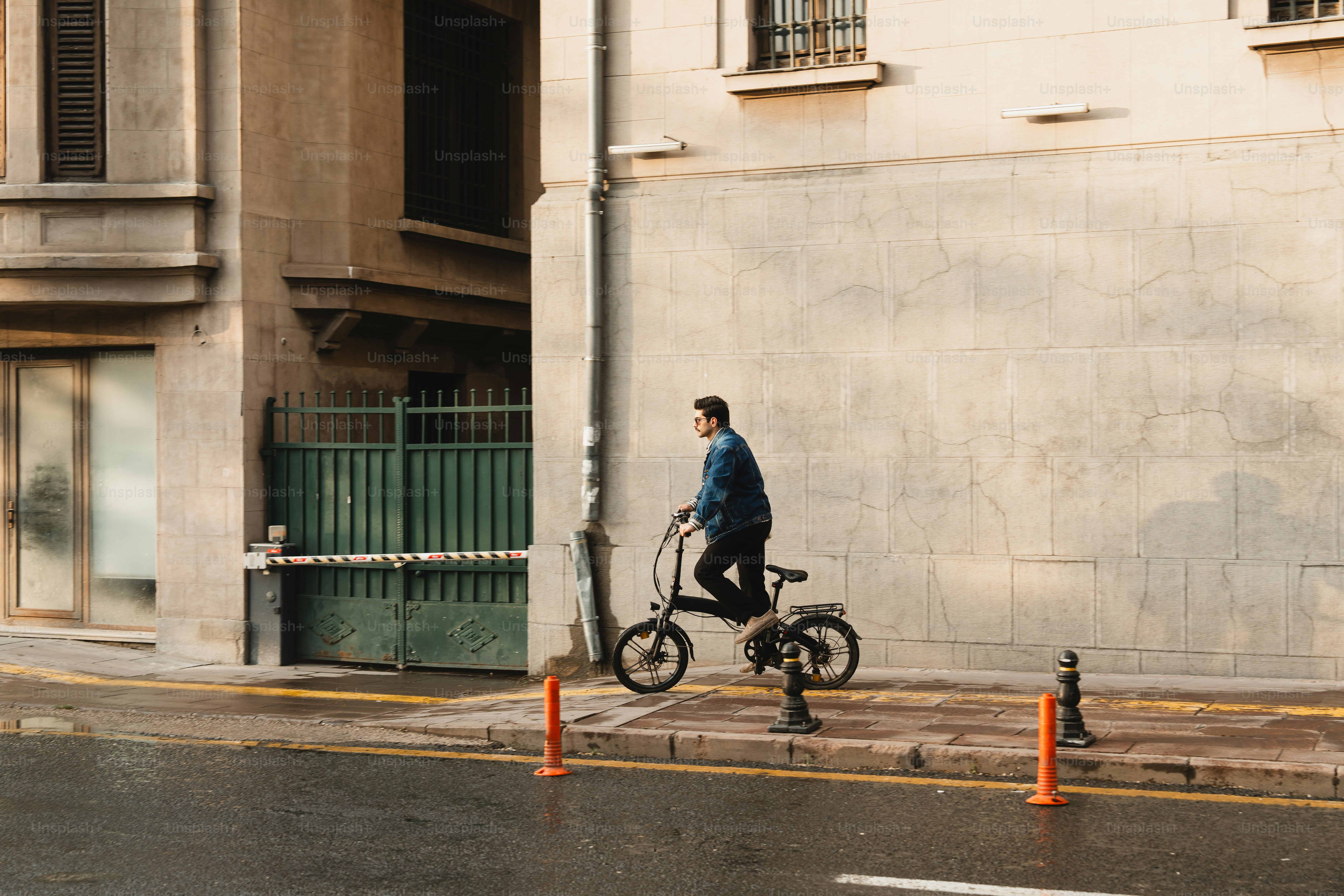 Hombre montando una bicicleta plegable en una acera de la ciudad