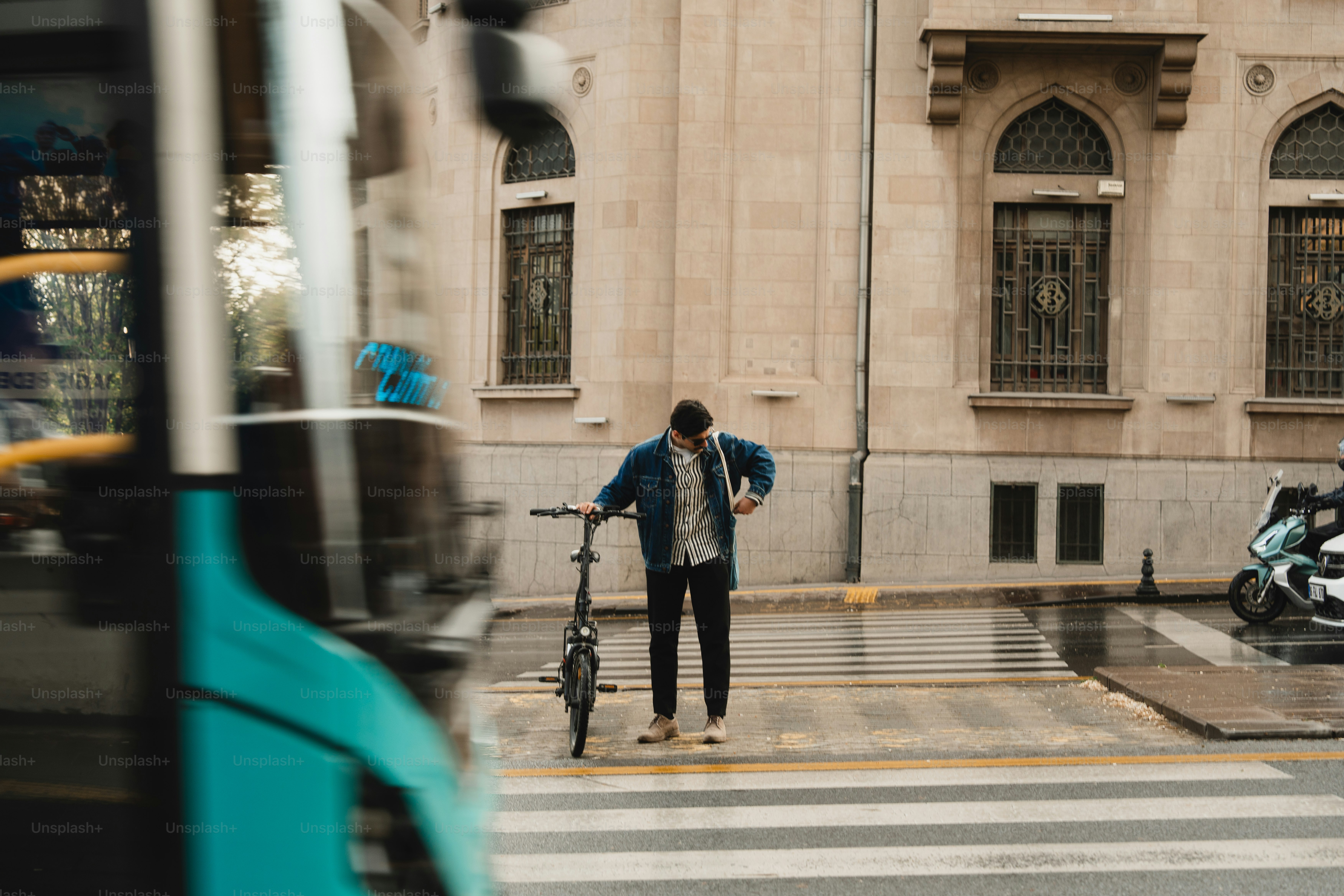 Hombre con bicicleta espera en el paso de peatones cerca del autobús
