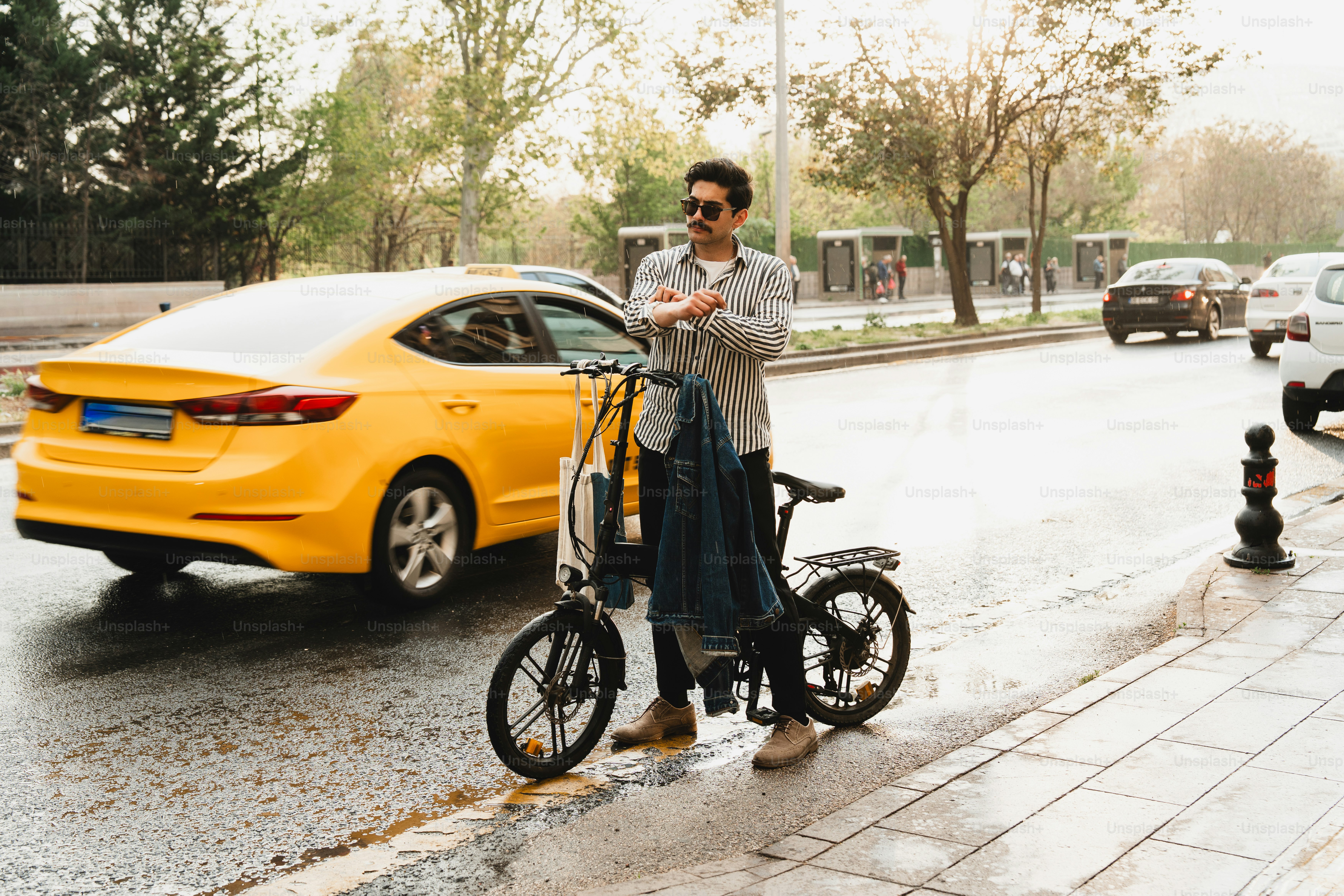 Hombre con bicicleta en una calle mojada de la ciudad con tráfico