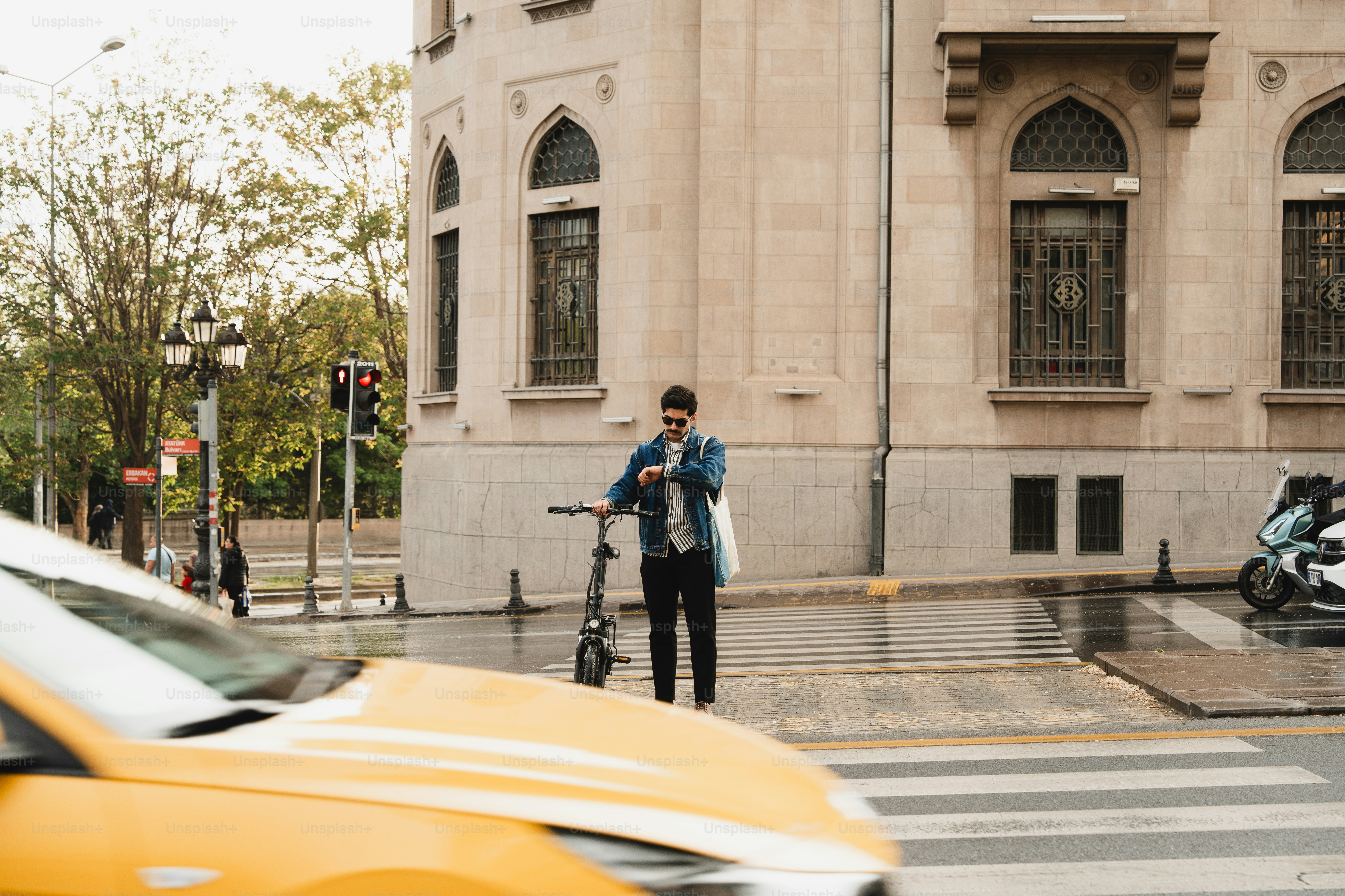 Hombre con scooter revisa el teléfono cerca del edificio y la calle.