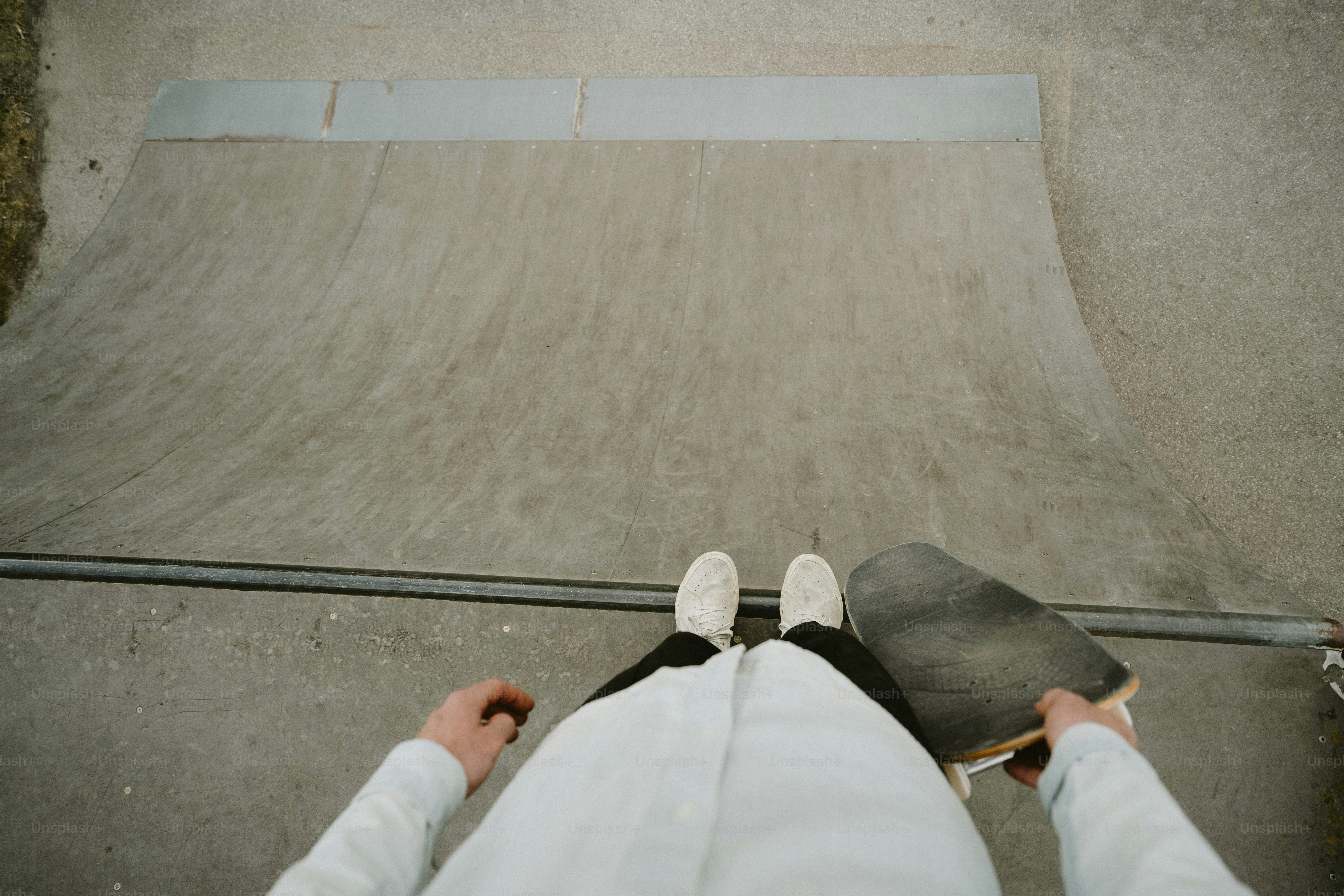 Pessoa em pé com skate na rampa do skatepark