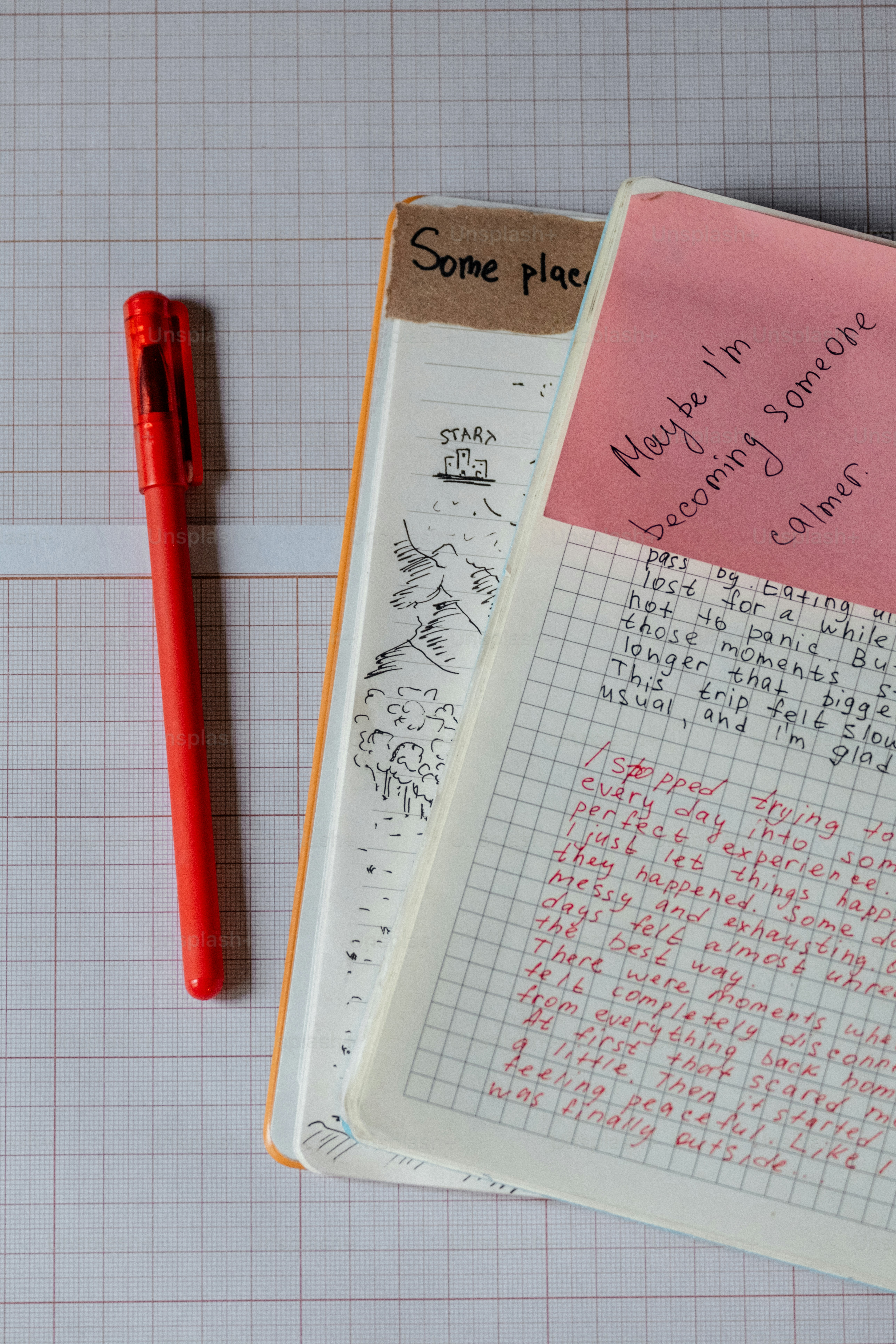 Deux carnets ouverts avec un stylo rouge sur du papier grillé.