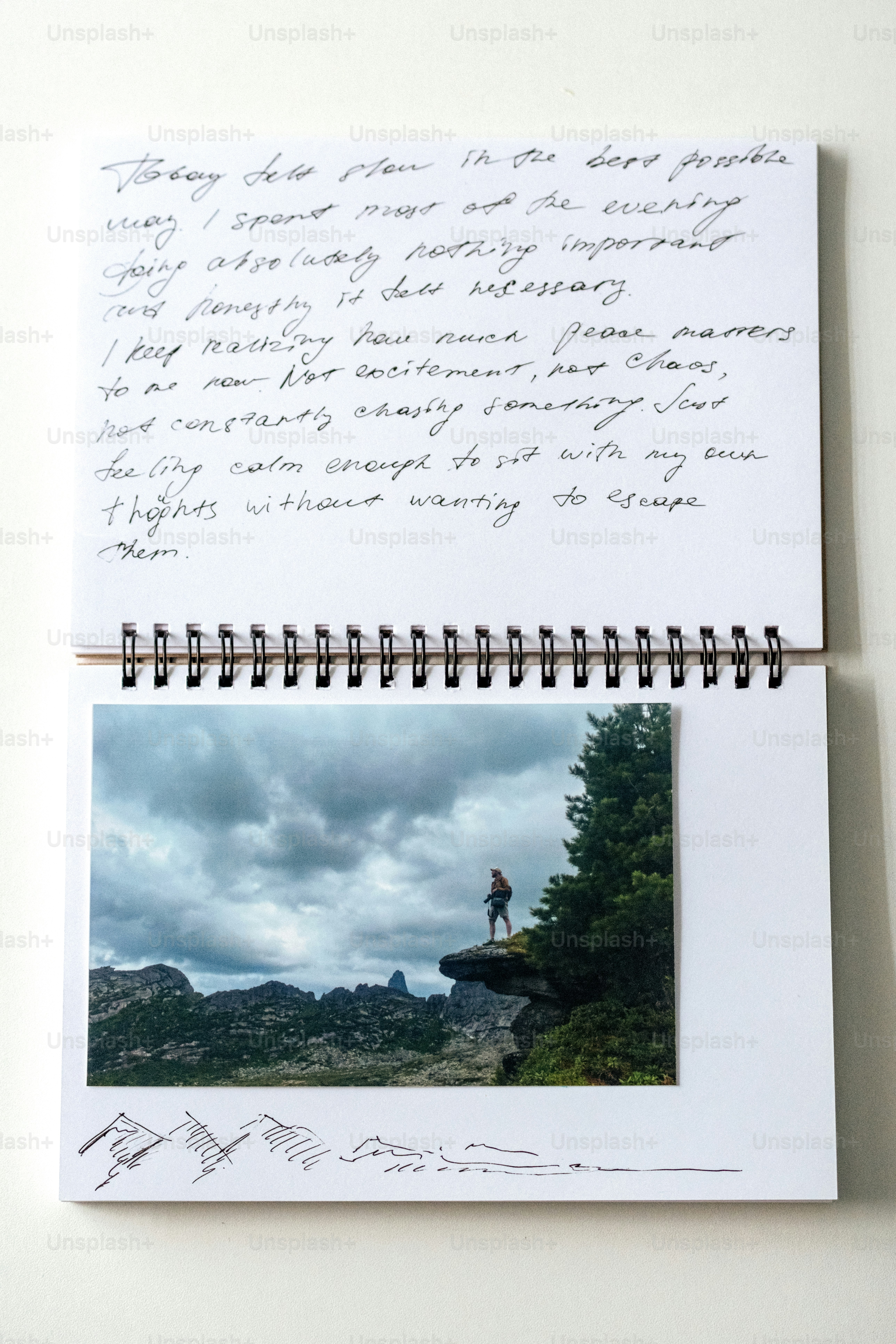 Un carnet ouvert affiche un texte manuscrit et une photo de falaise de montagne.