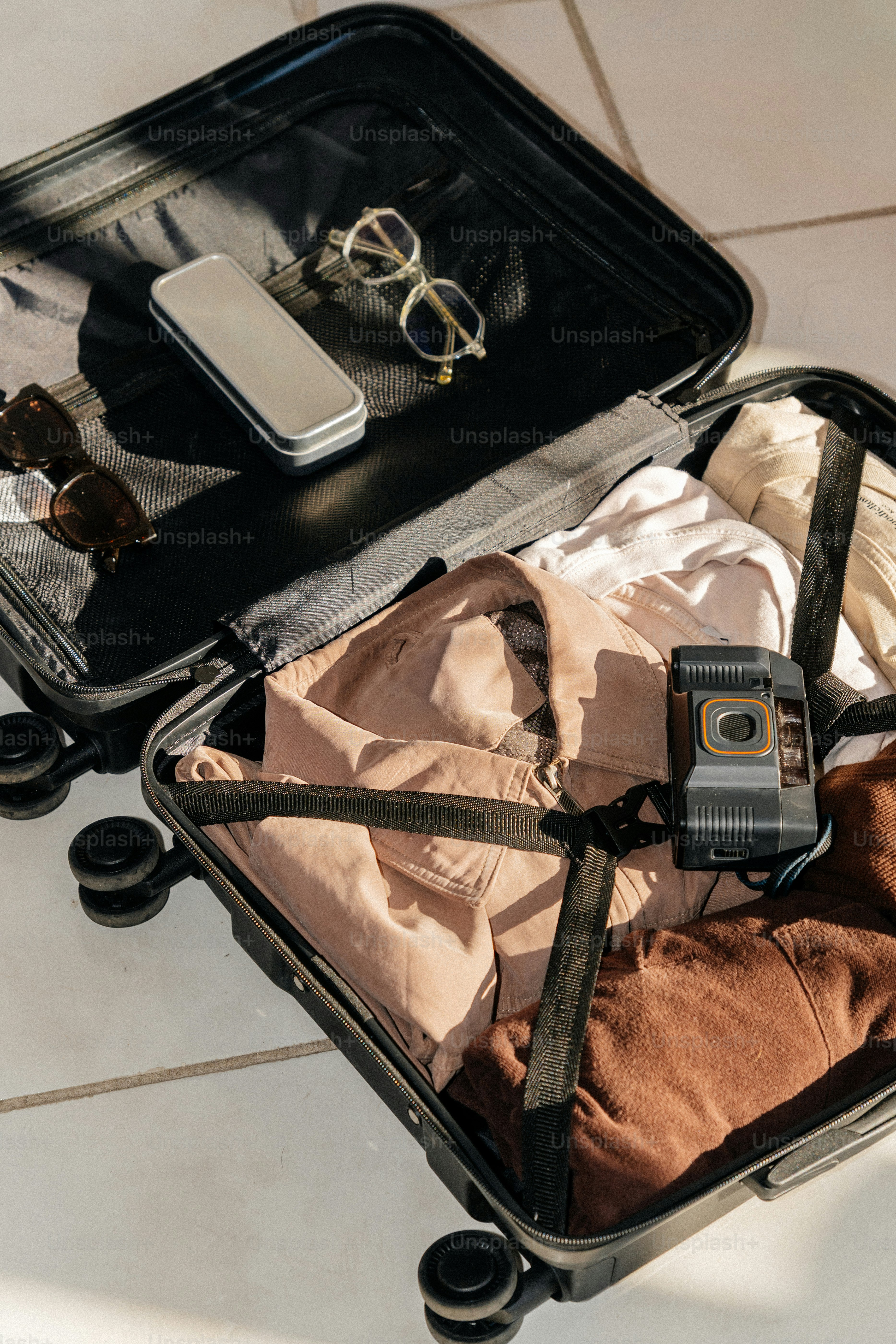 Open suitcase packed with clothes and accessories.