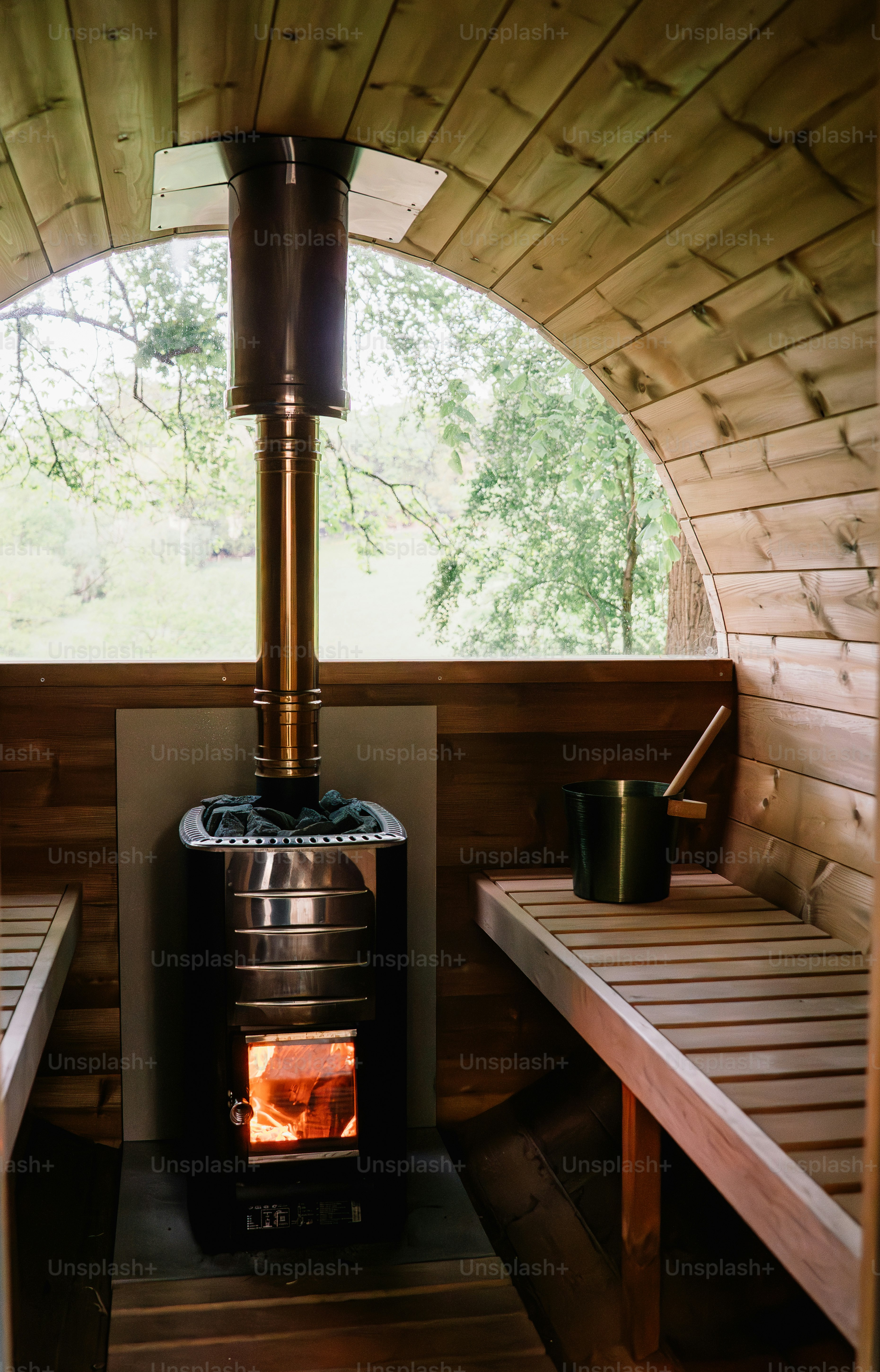 Interior sauna kayu dengan kompor yang menyala.