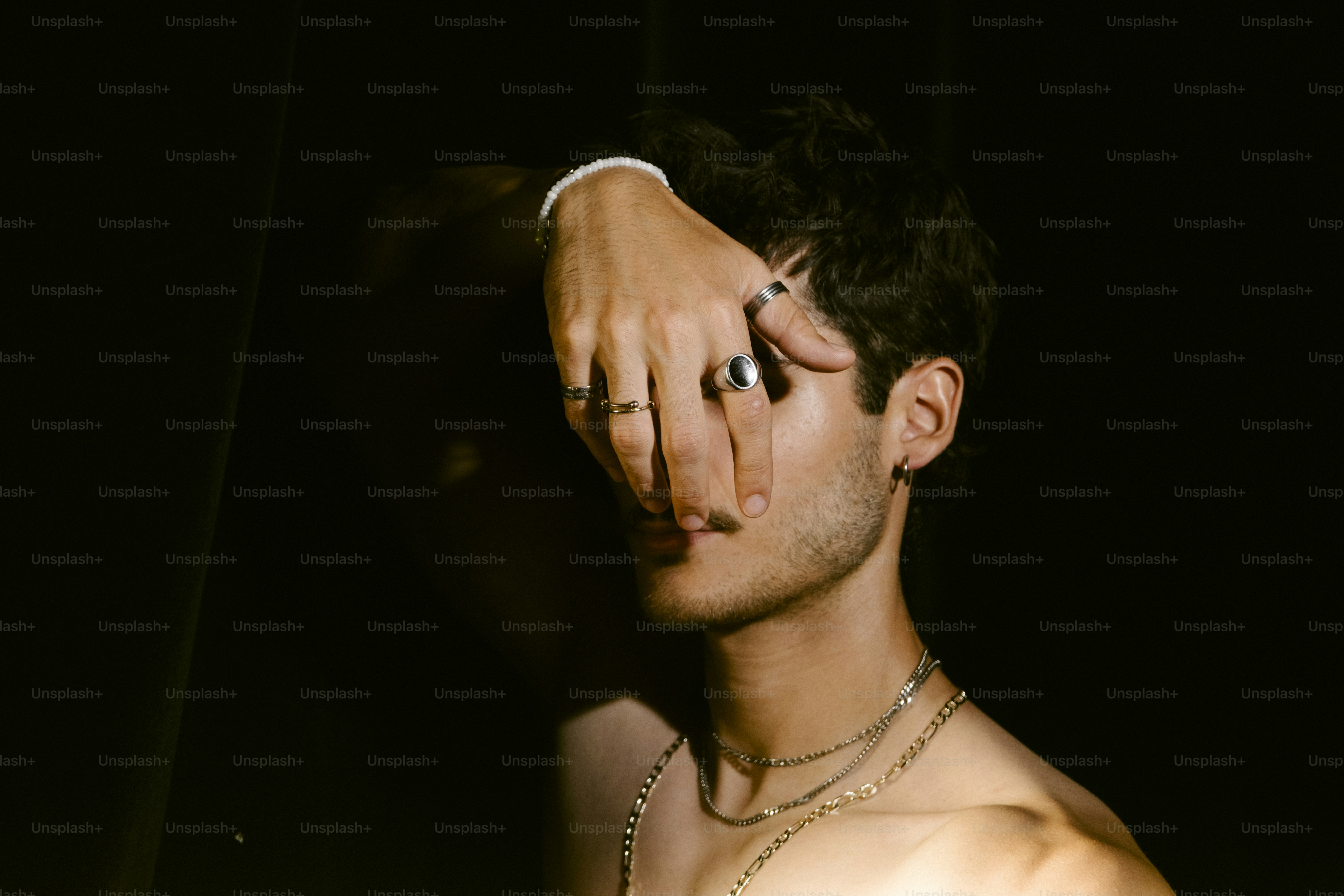 Man covering face with hand, wearing jewelry