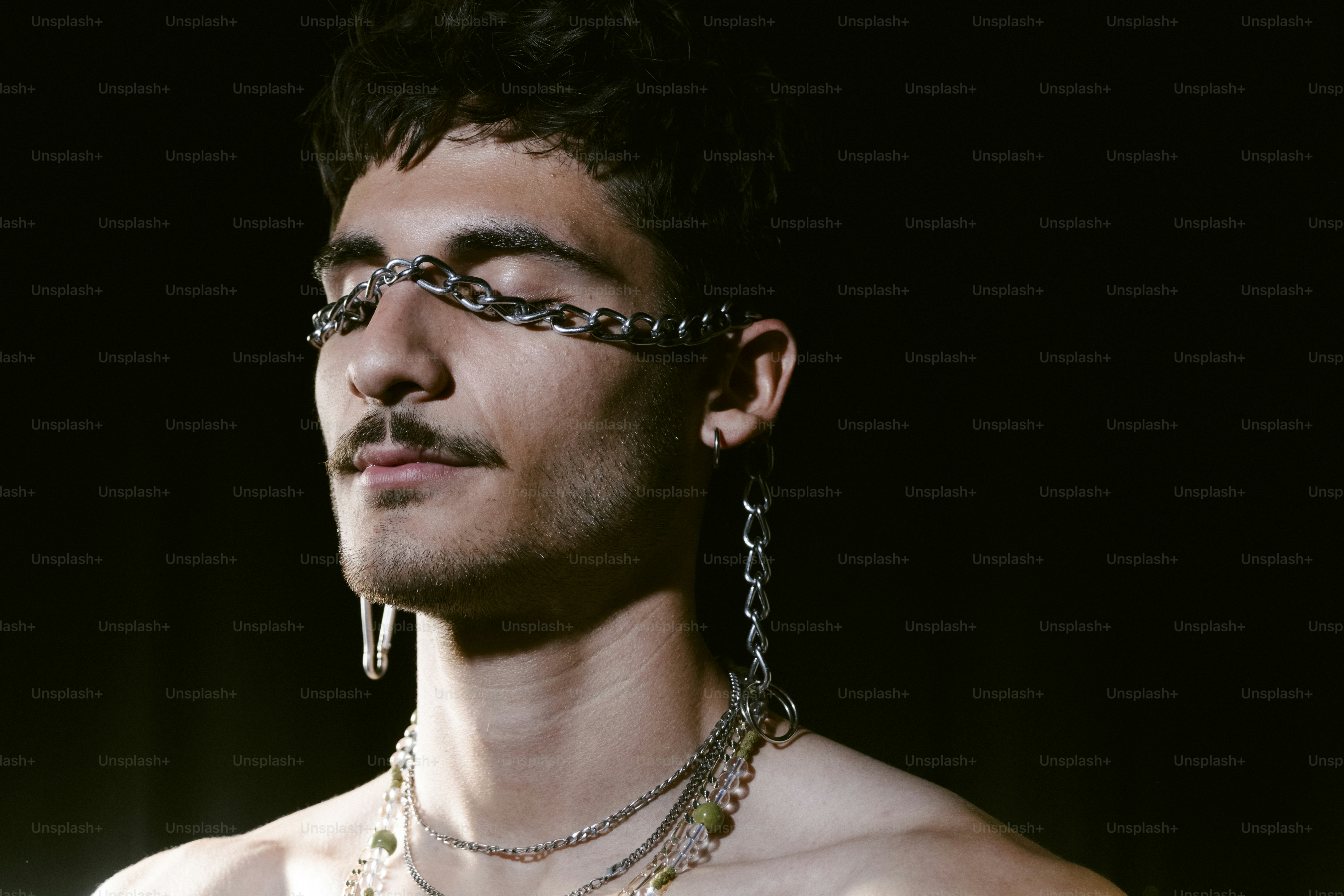 Man with chains across eyes and dangling earrings