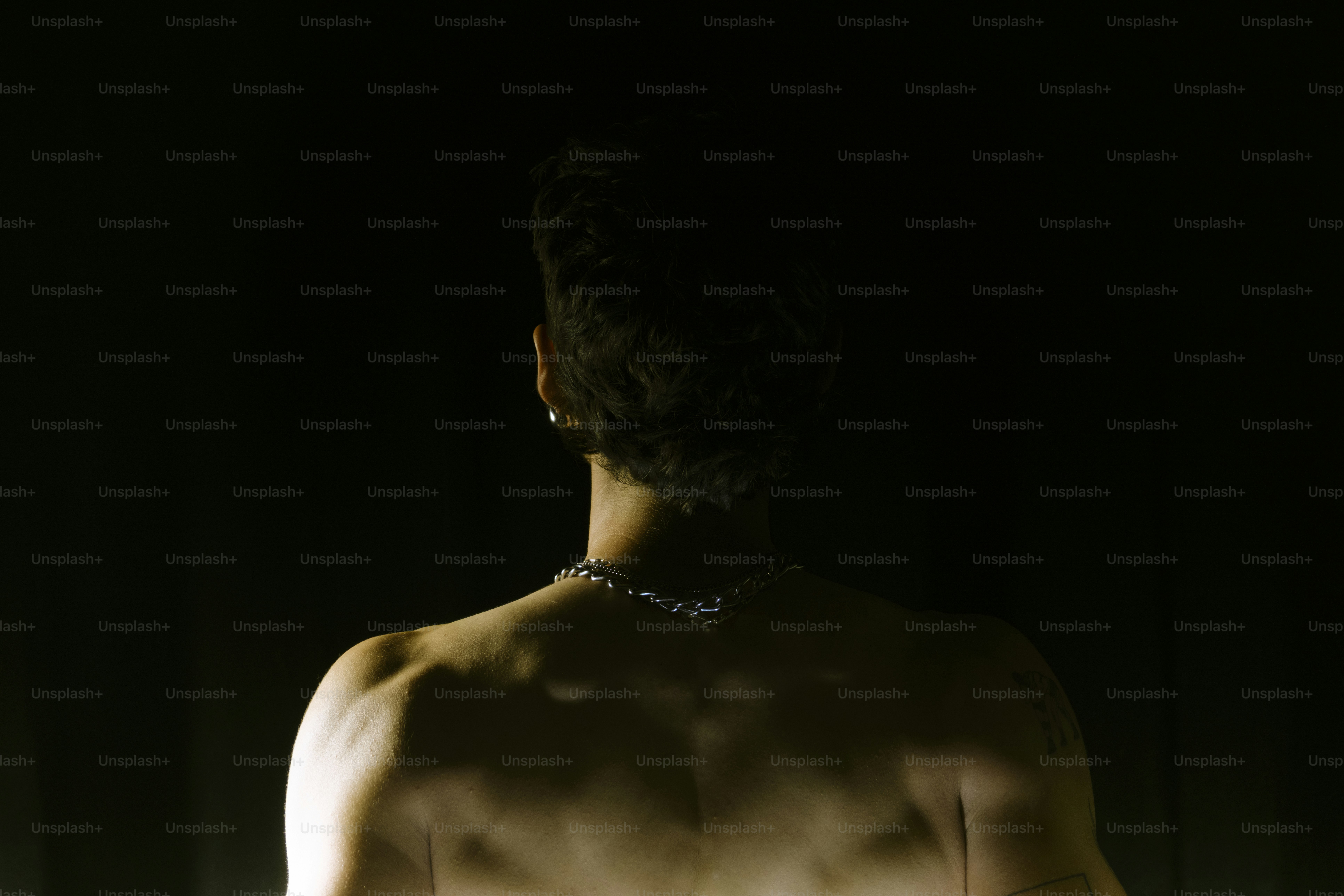 Man's back with a necklace in darkness
