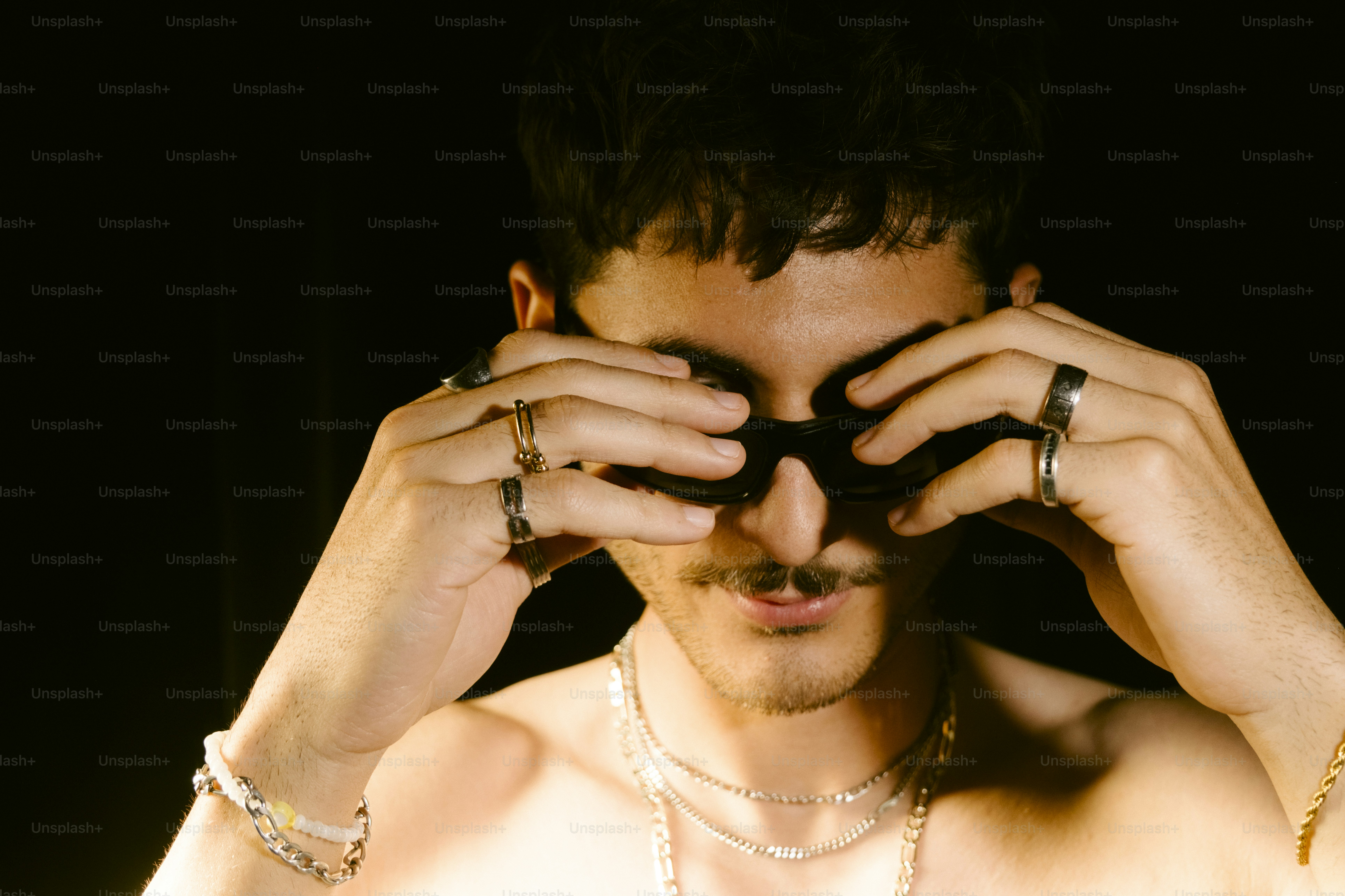 Man adjusting sunglasses against a dark background