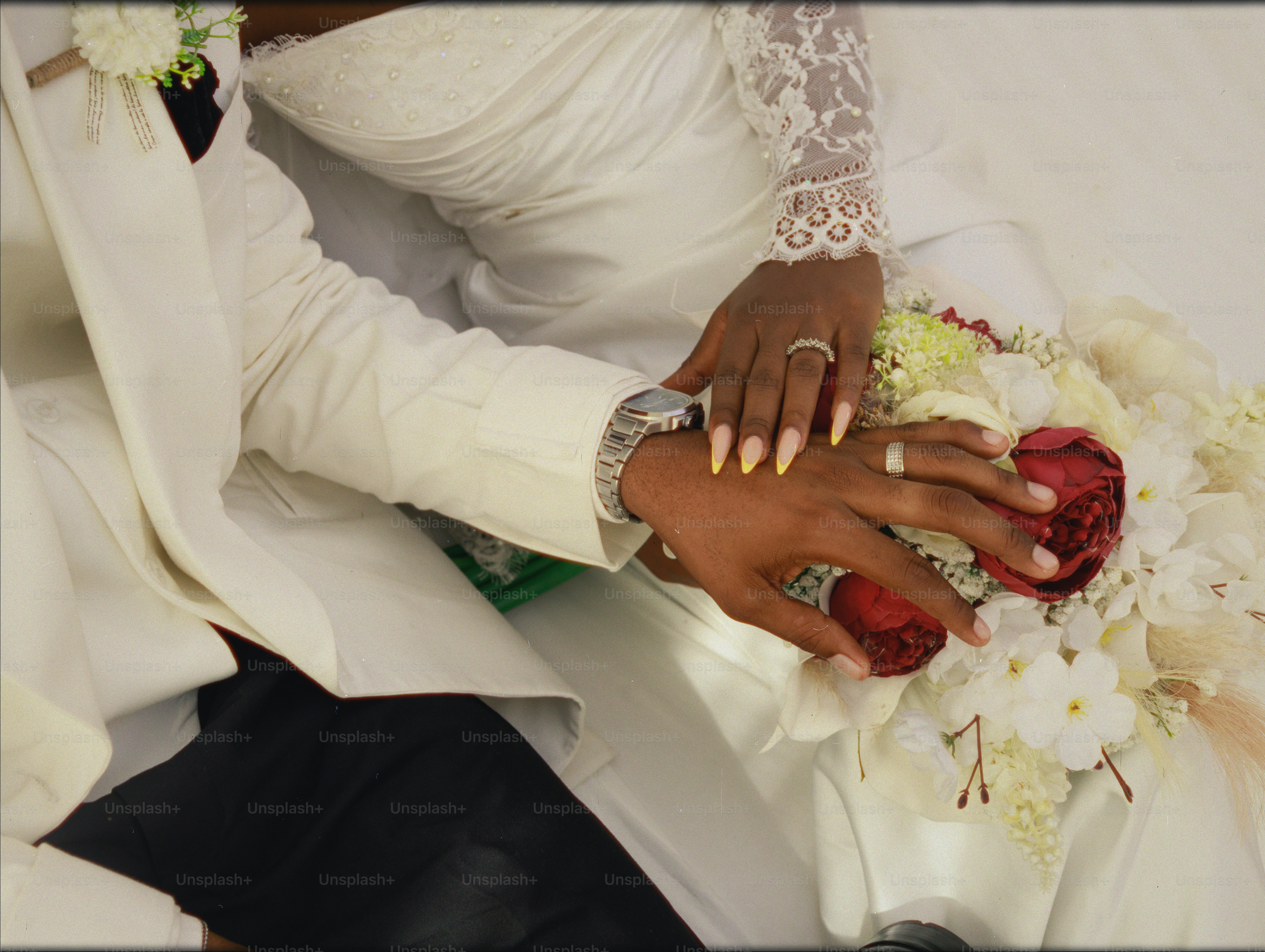 Bride and groom's hands with wedding rings and a bouquet.