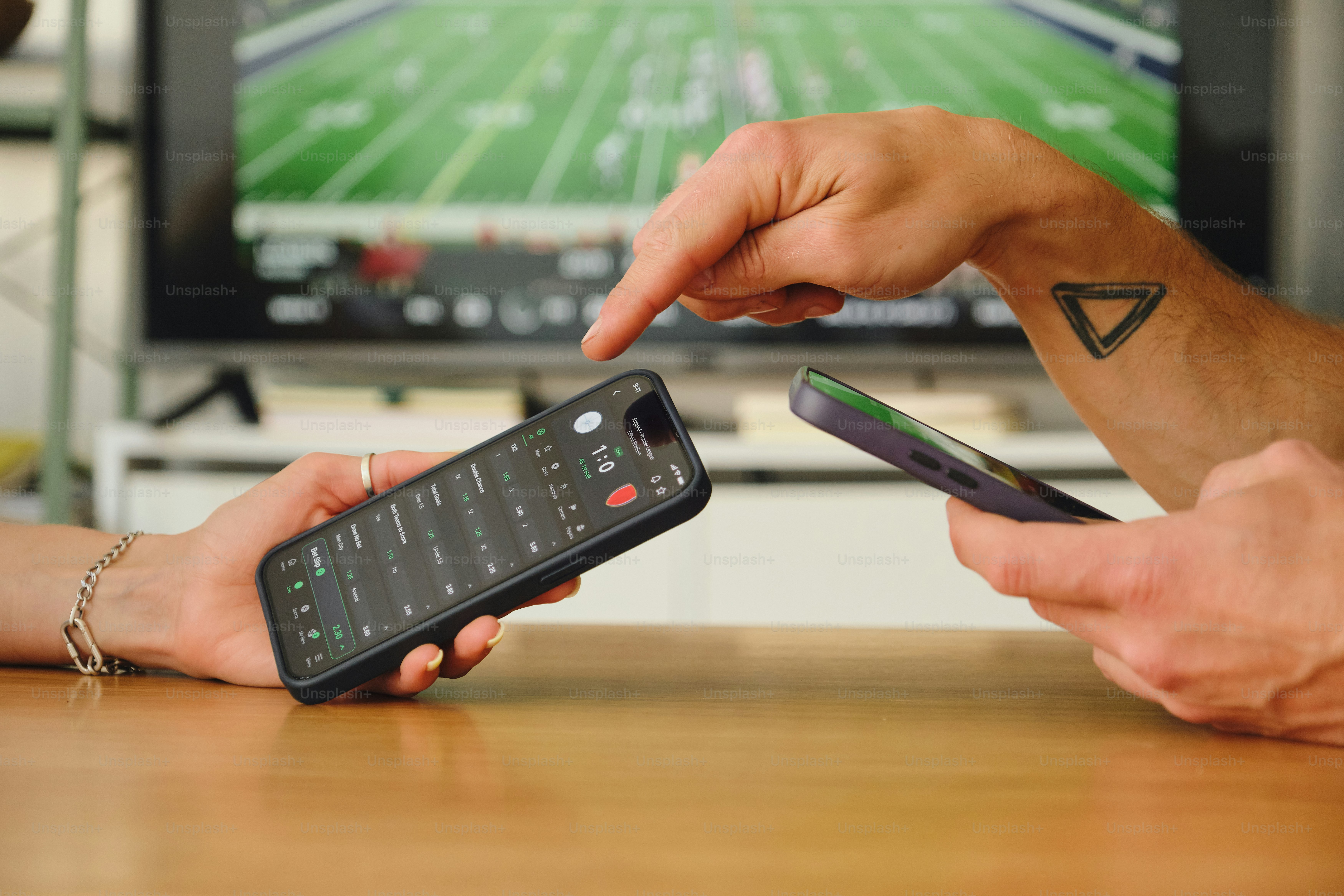 Two people interacting with smartphones while watching tv.