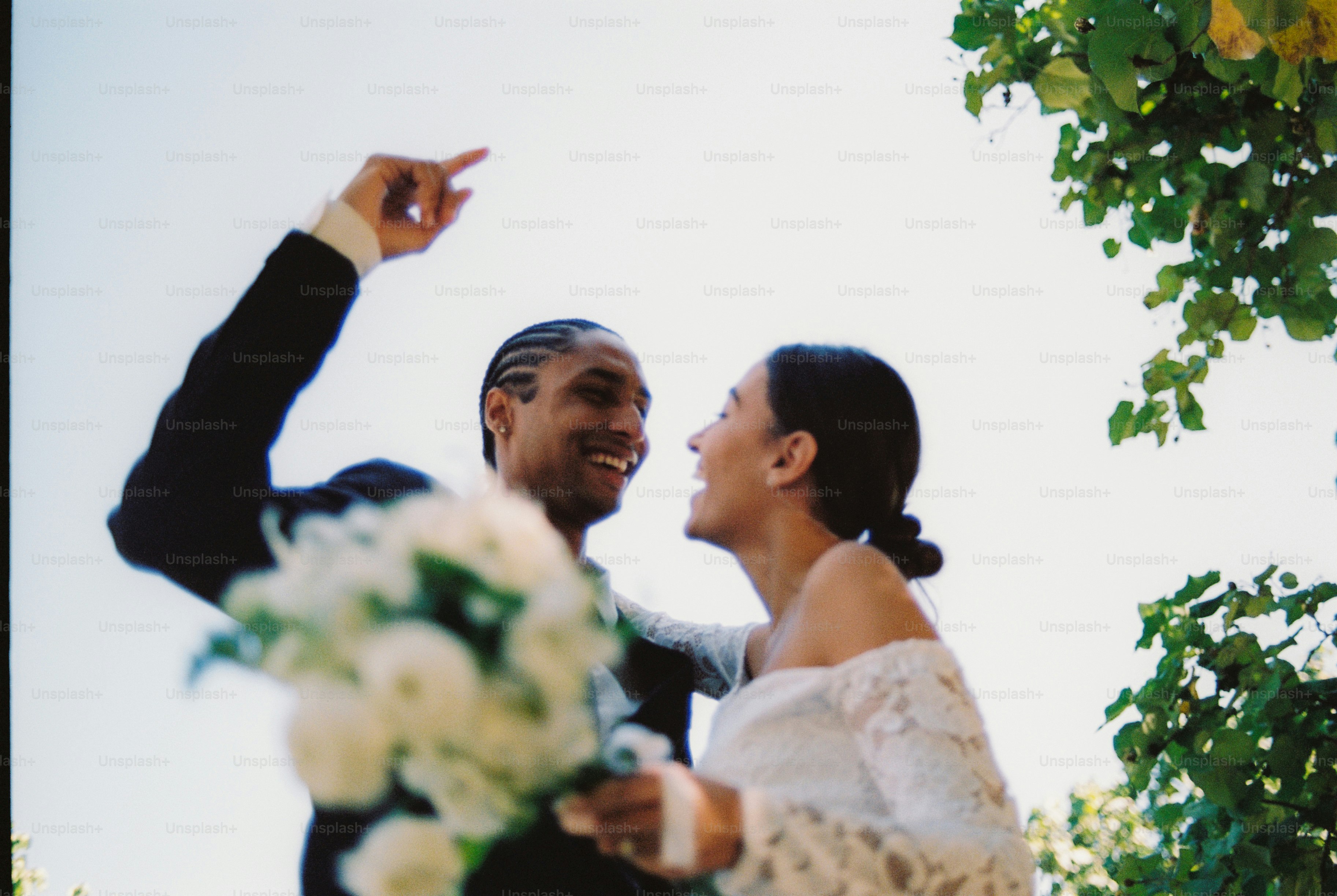 Joyful couple smiling at each other, holding a white bouquet. photo ...