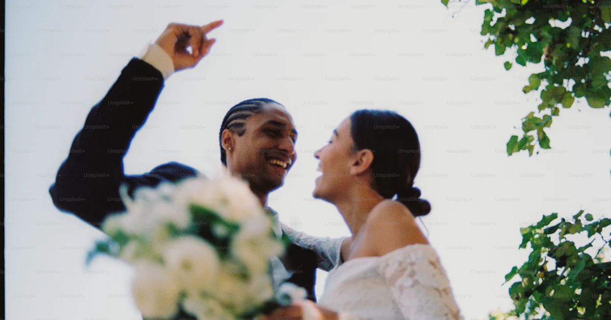 Joyful couple smiling at each other, holding a white bouquet. photo ...