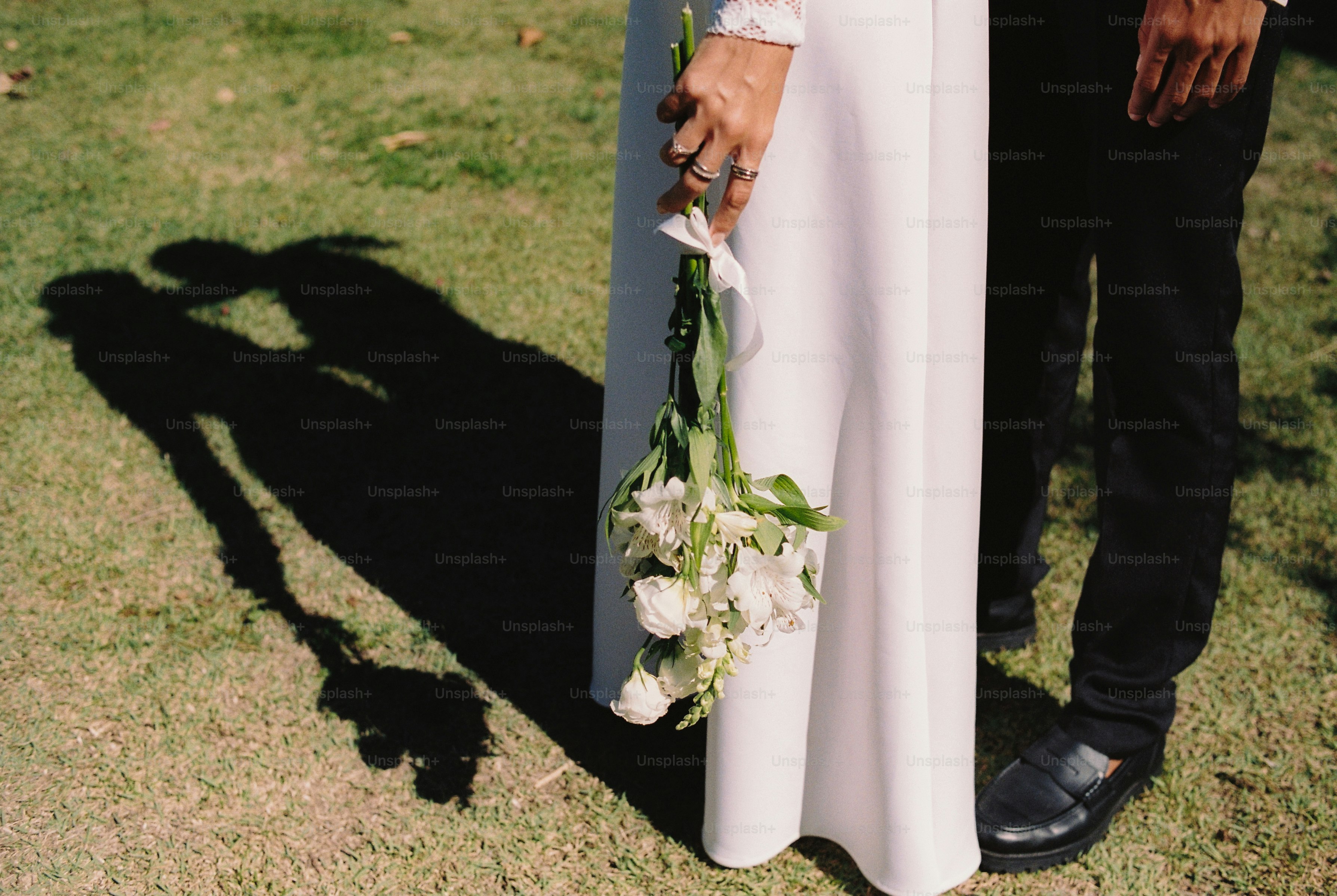 Bayangan pasangan pengantin dan karangan bunga di atas rumput