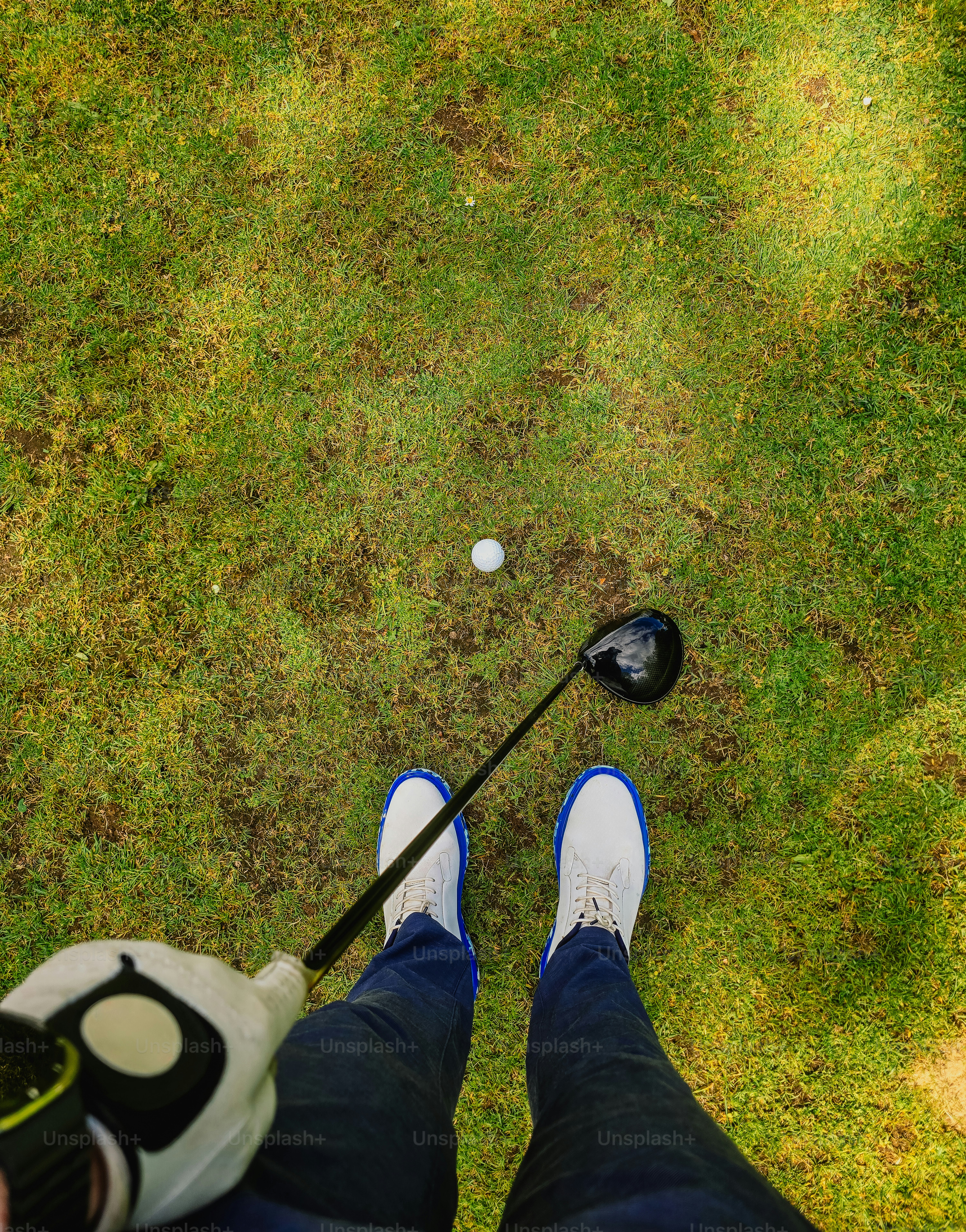 Golfer's view of ball and club on green grass.