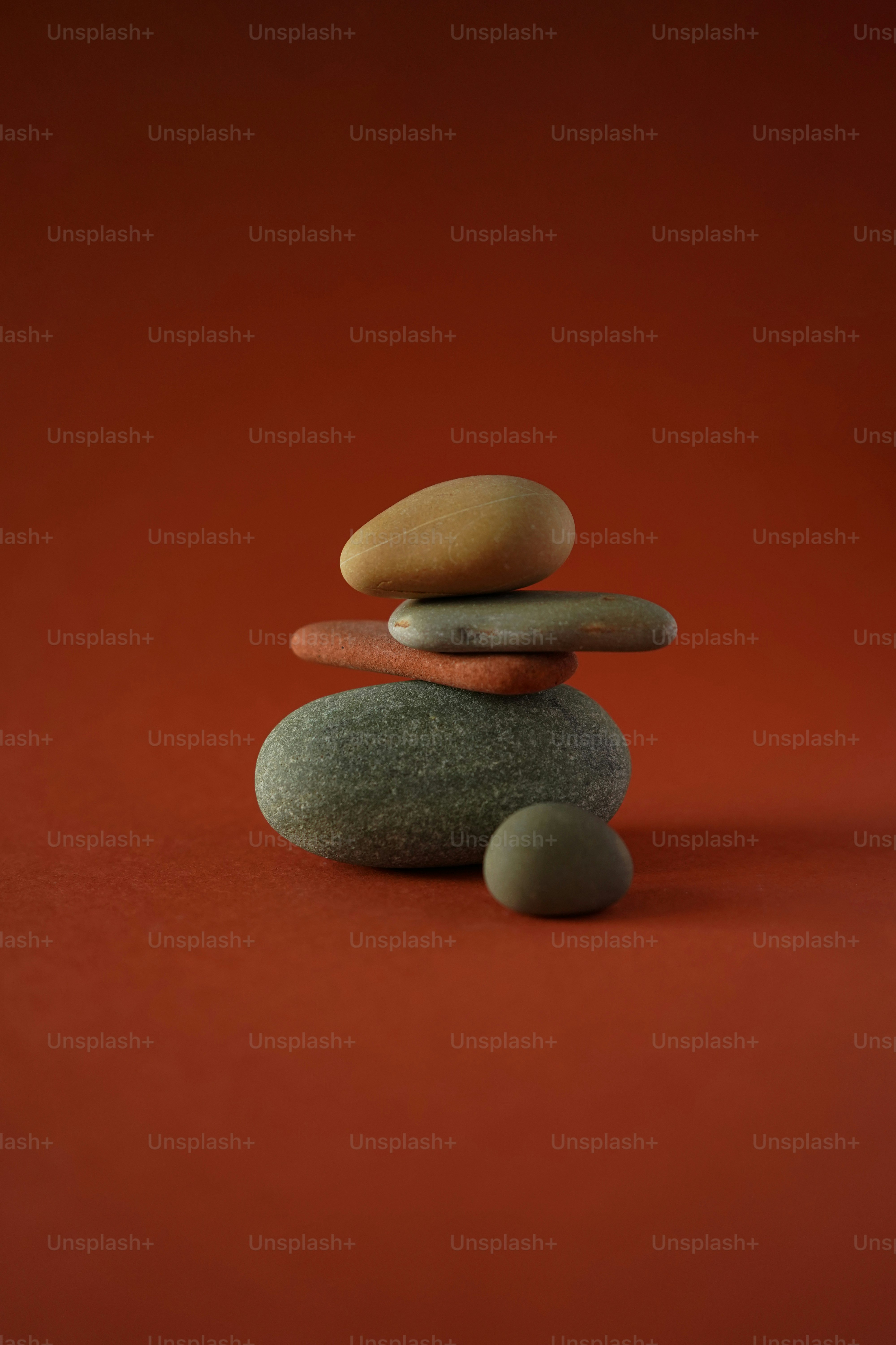 Pedras lisas empilhadas equilibradas sobre um fundo marrom-avermelhado.